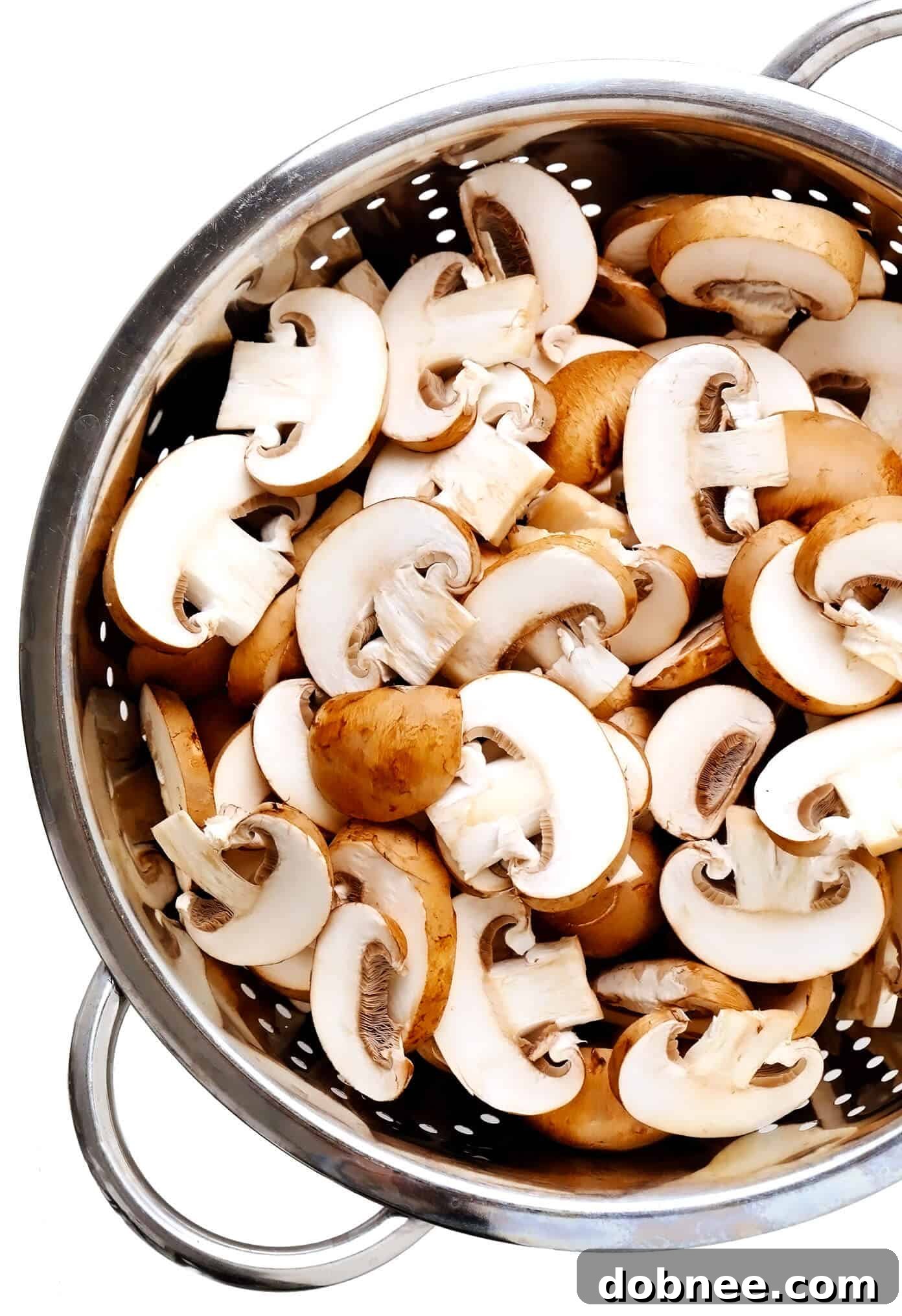 Fresh baby bella (cremini) mushrooms in a colander, ready for preparation