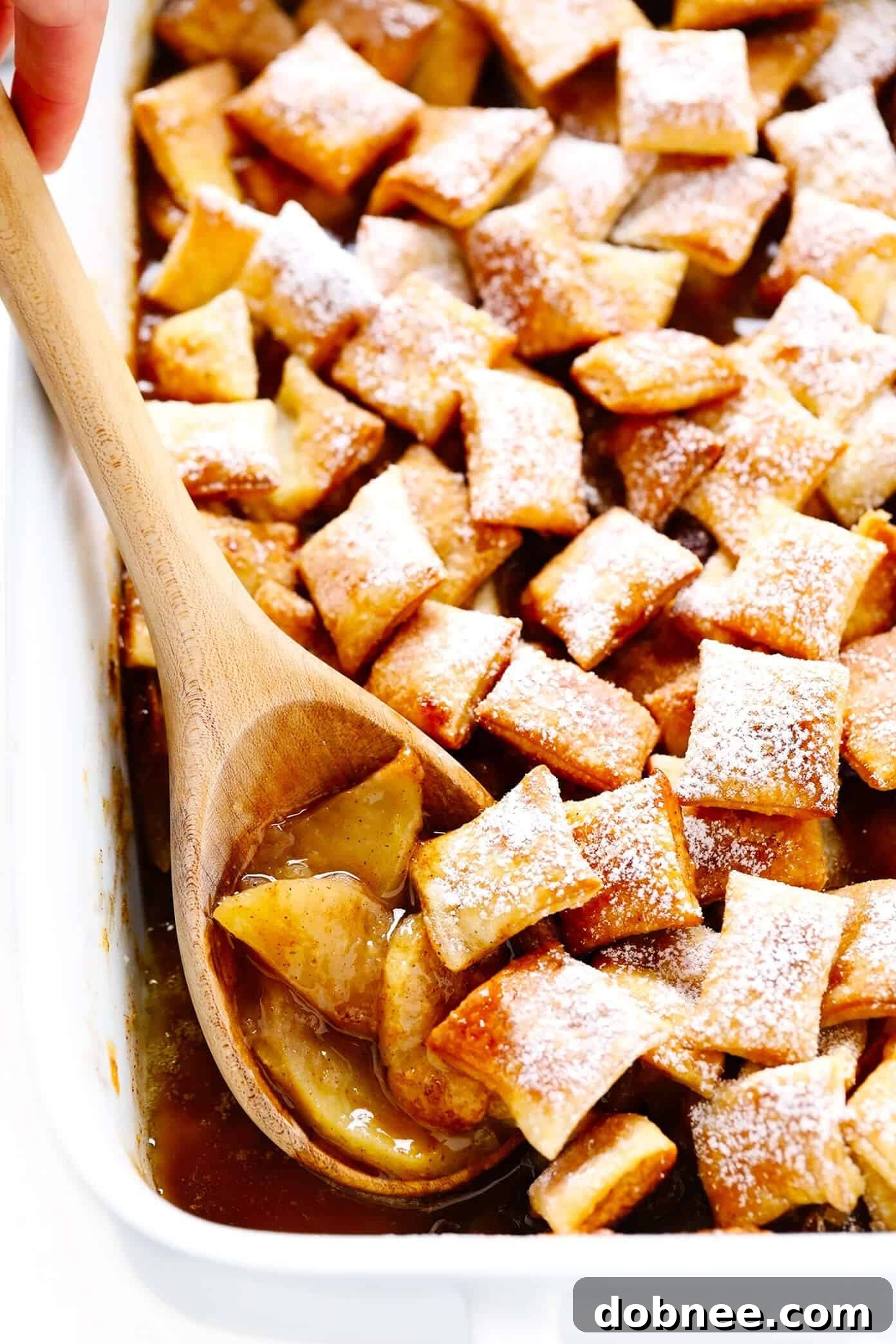 Easy Apple Pandowdy: A simple baked apple cinnamon pie filling topped with toasted puff pastry bites and powdered sugar. Delicious with vanilla ice cream, perfect for any occasion. Puff Pastry Topped Apple Pandowdy, a simple baked apple dessert perfect for holidays or any cozy occasion.