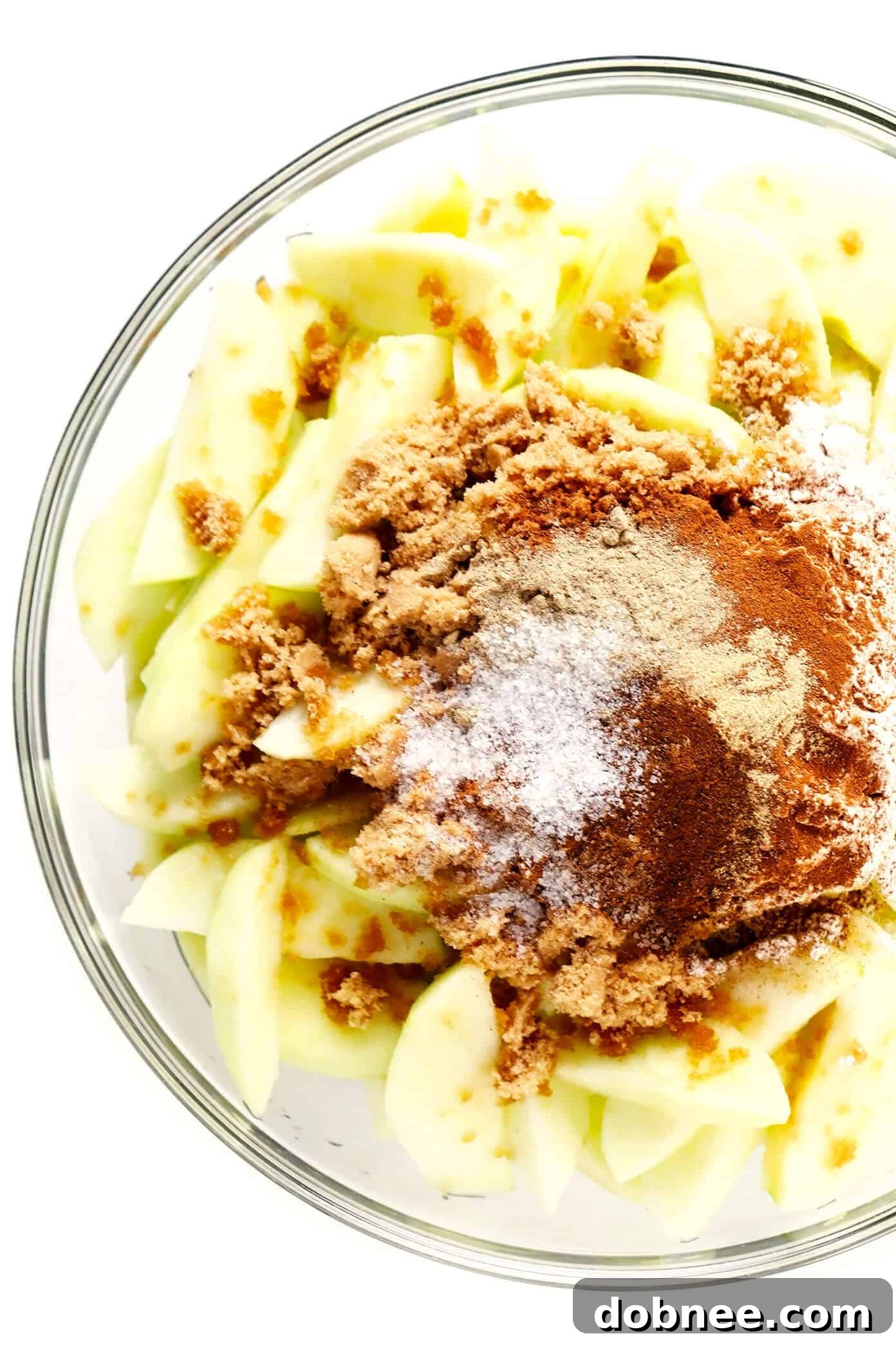 Fresh apple pie filling ingredients, ready for an easy pandowdy recipe. Bowl of freshly prepared apple pie filling ingredients, including sliced apples, lemon, sugar, and spices.