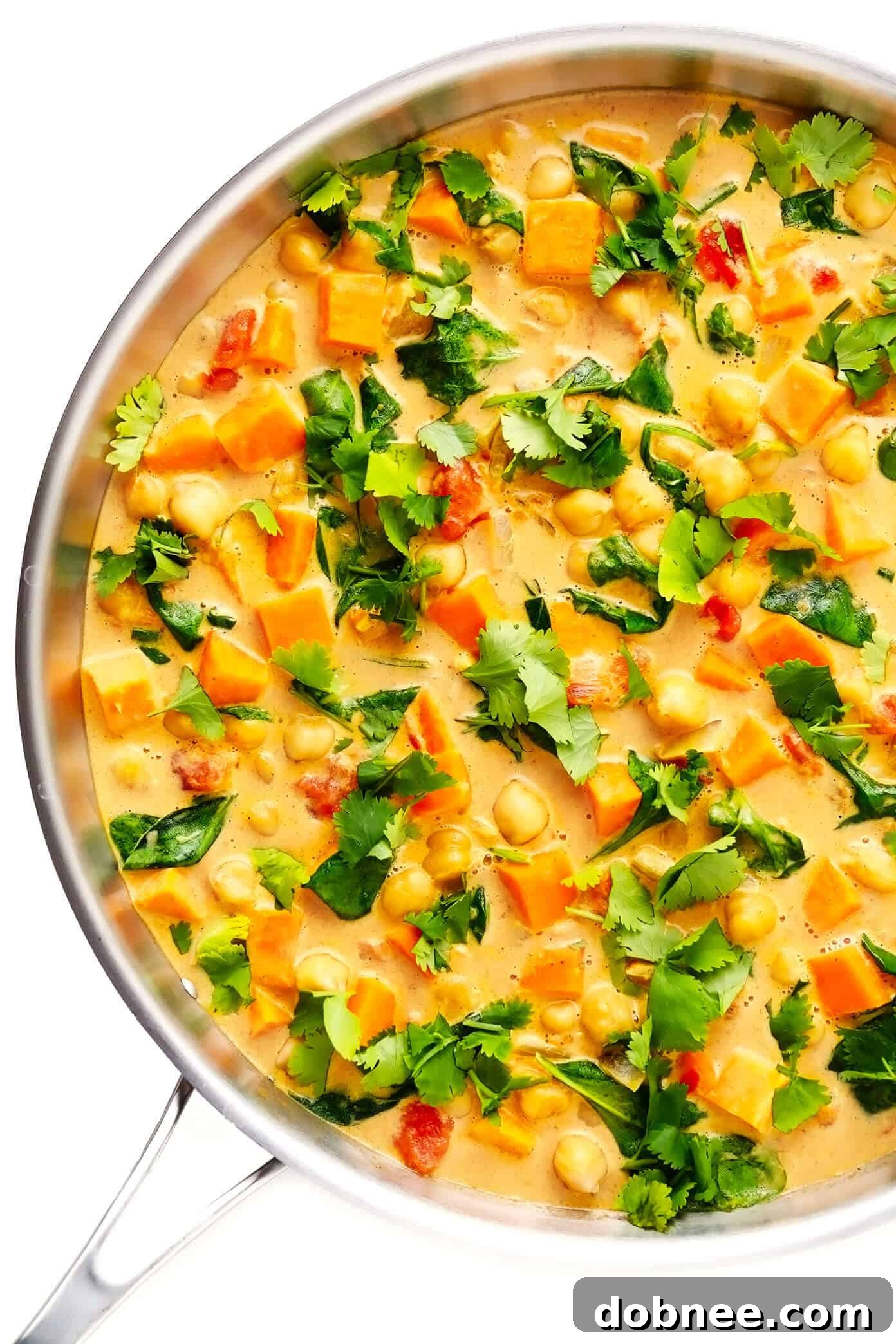 Sweet Potato Chickpea Coconut Curry in a large sauté pan, garnished with fresh cilantro, ready for serving. A wholesome, comforting vegan and gluten-free dinner.