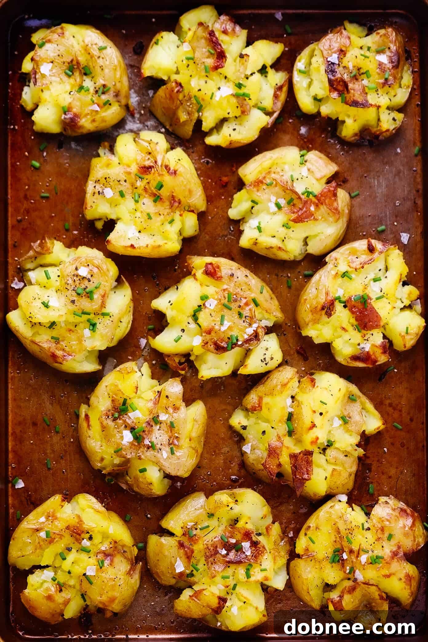 Freshly baked garlic smashed potatoes, hot off the baking sheet and perfectly golden, ready to be served and enjoyed as a delicious and easy side dish.