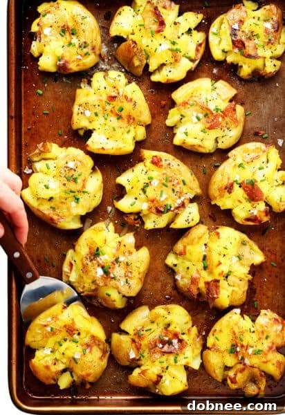 Smashed Potatoes garnished with fresh chives on a wooden board