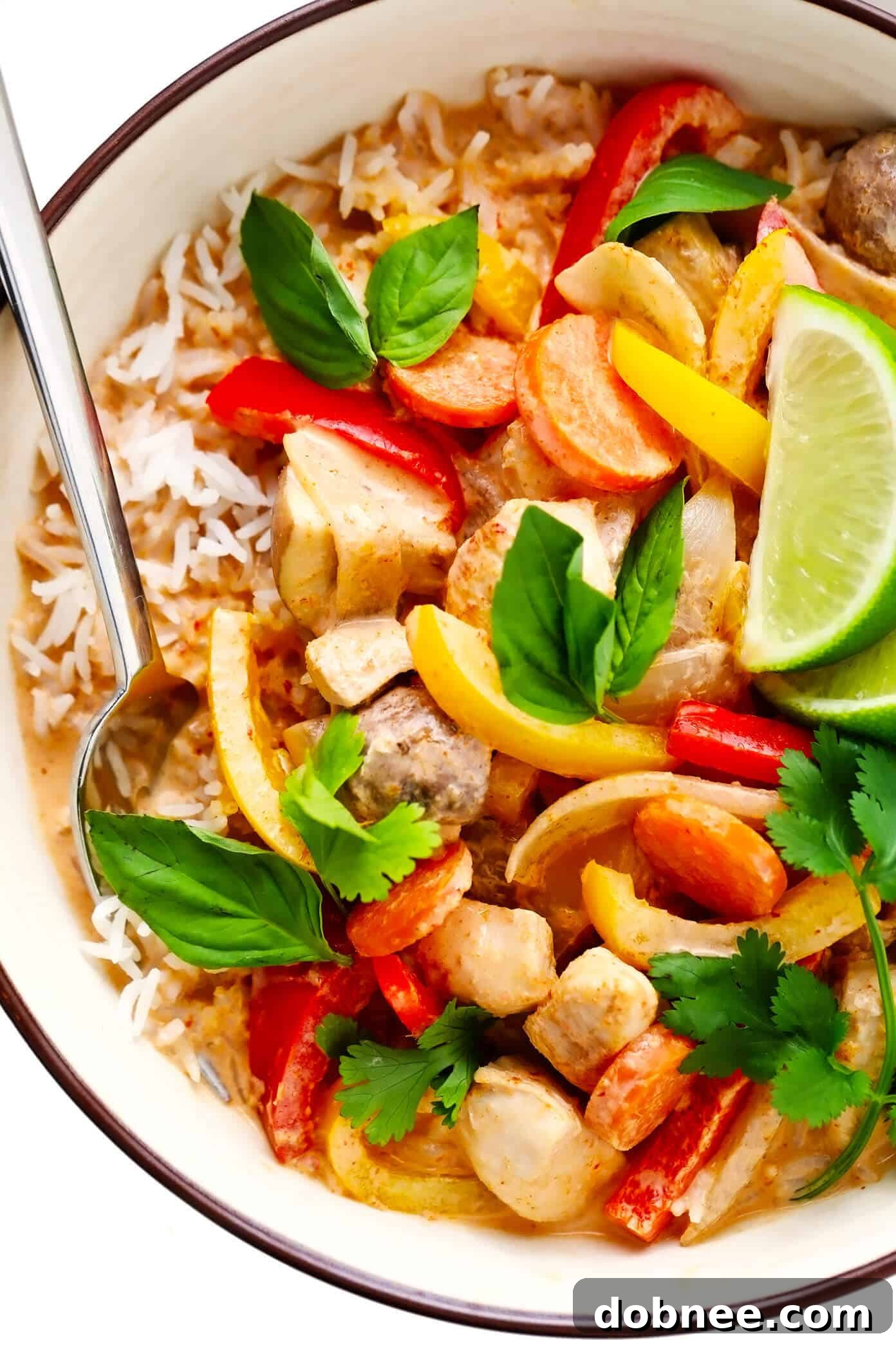 Close-up view of a bowl of Thai Chicken Curry with fluffy white rice, garnished with fresh herbs, ready to be enjoyed.