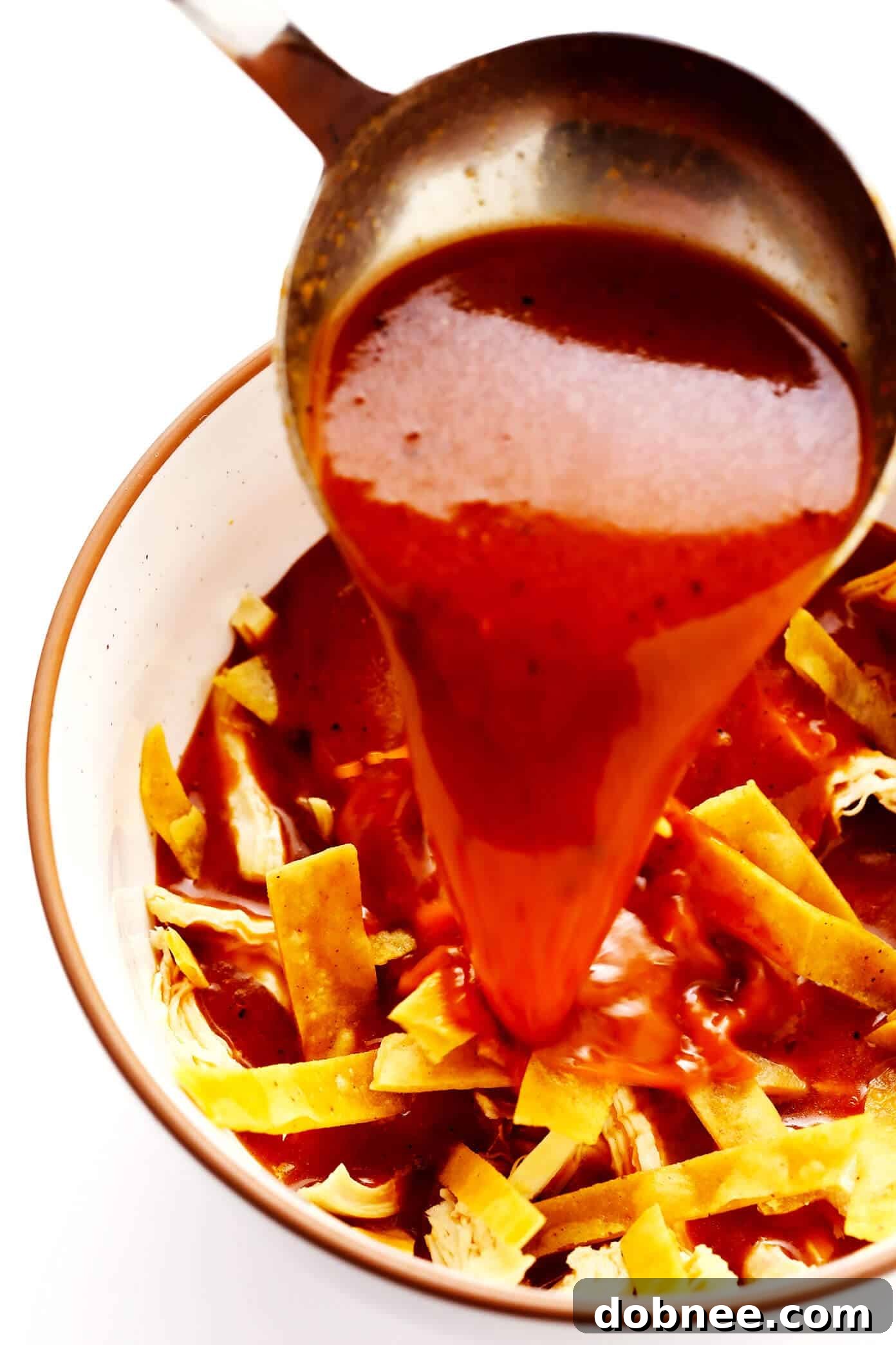 Pouring hot broth over tortilla strips to make authentic tortilla soup