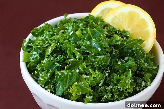 A top-down view of a fresh Lemon Parmesan Kale Salad, ready to be served. The dressing glistens on the dark green leaves.