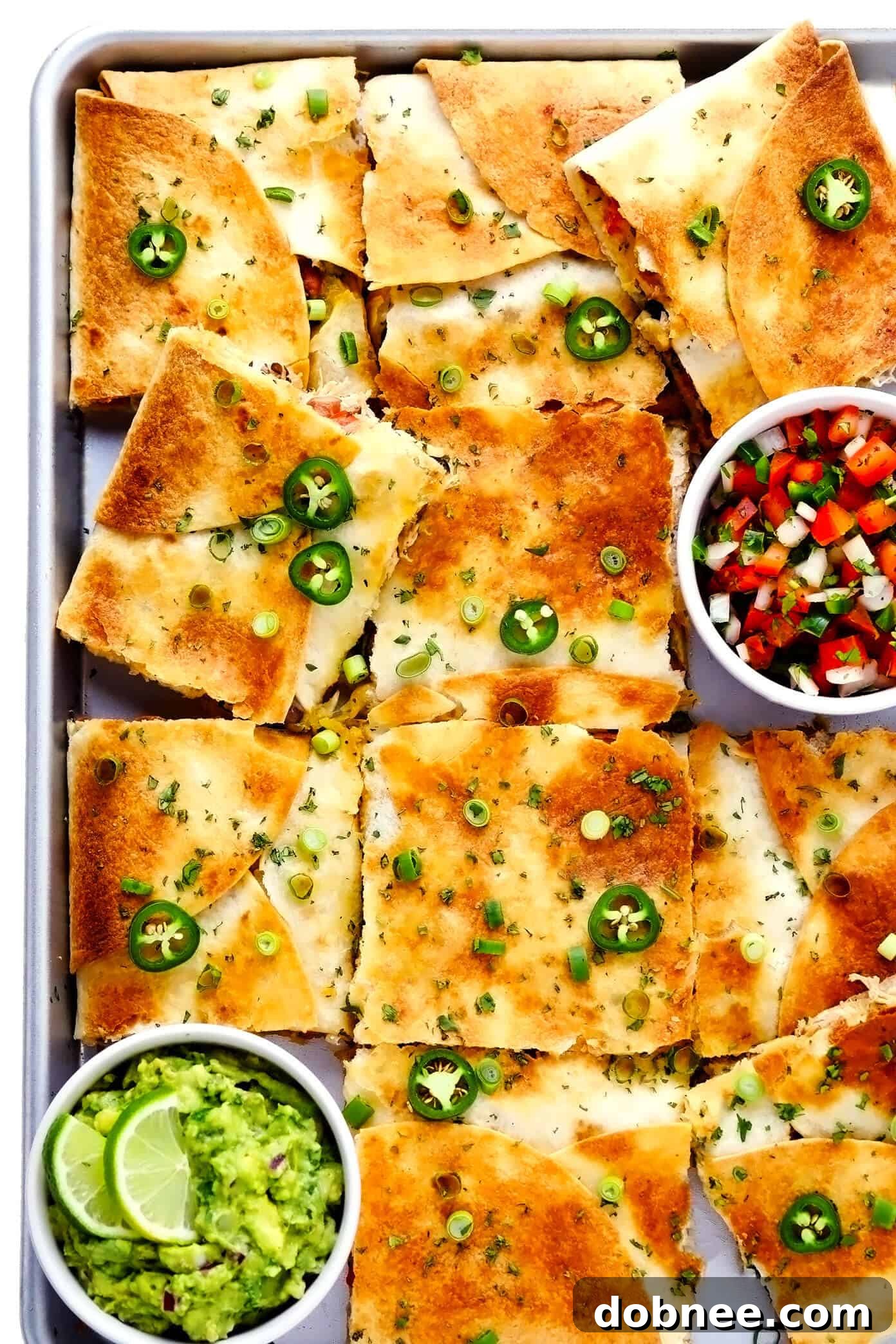Chicken Sheet Pan Quesadilla with Guacamole and Pico de Gallo served on a cutting board, ready for a party.