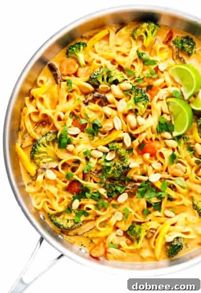 A bowl of Saucy Thai Curried Peanut Noodles, garnished with fresh cilantro and lime.