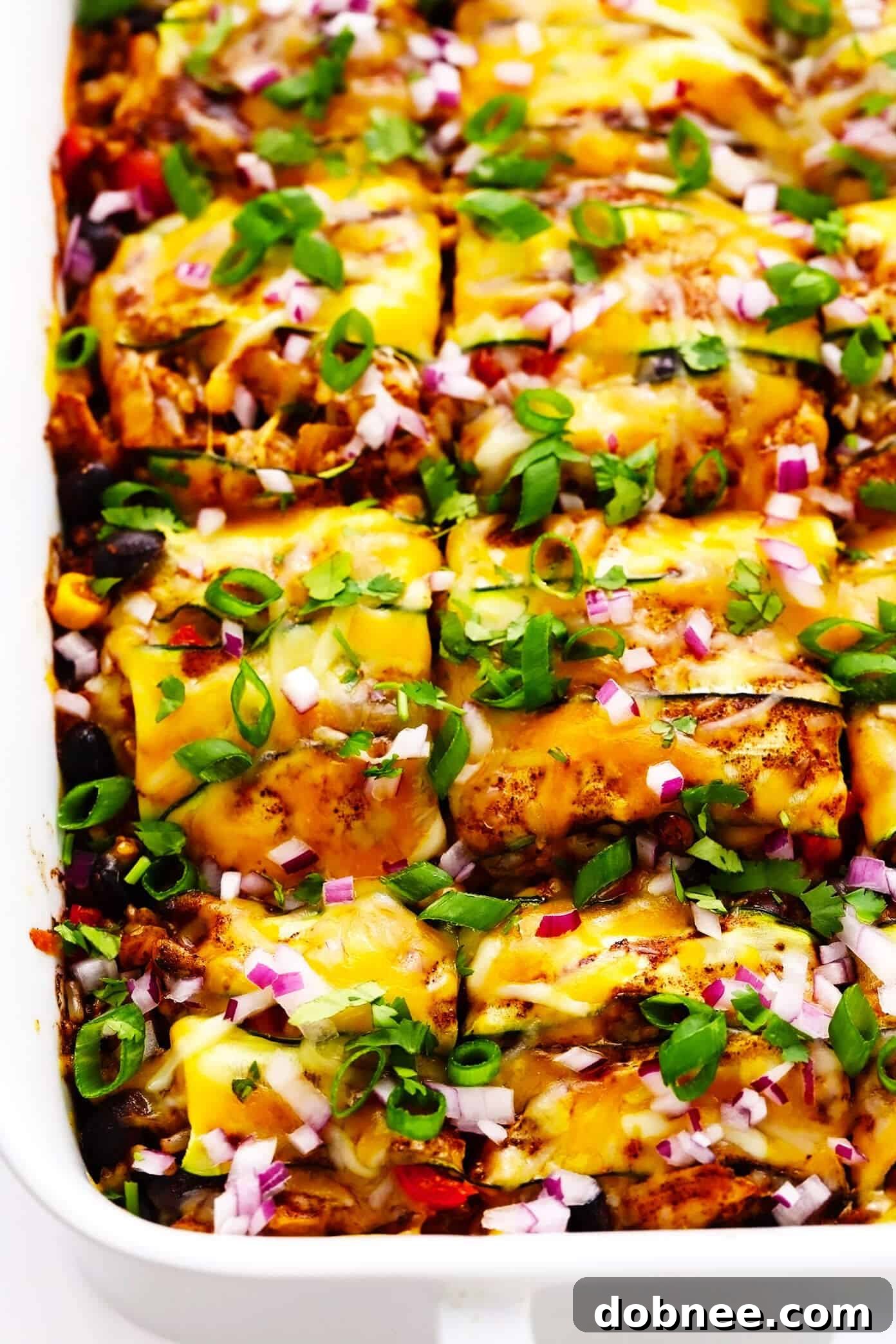 Stacked Zucchini Enchilada Casserole with vibrant layers of zucchini, cheese, and sauce, garnished with fresh cilantro and avocado