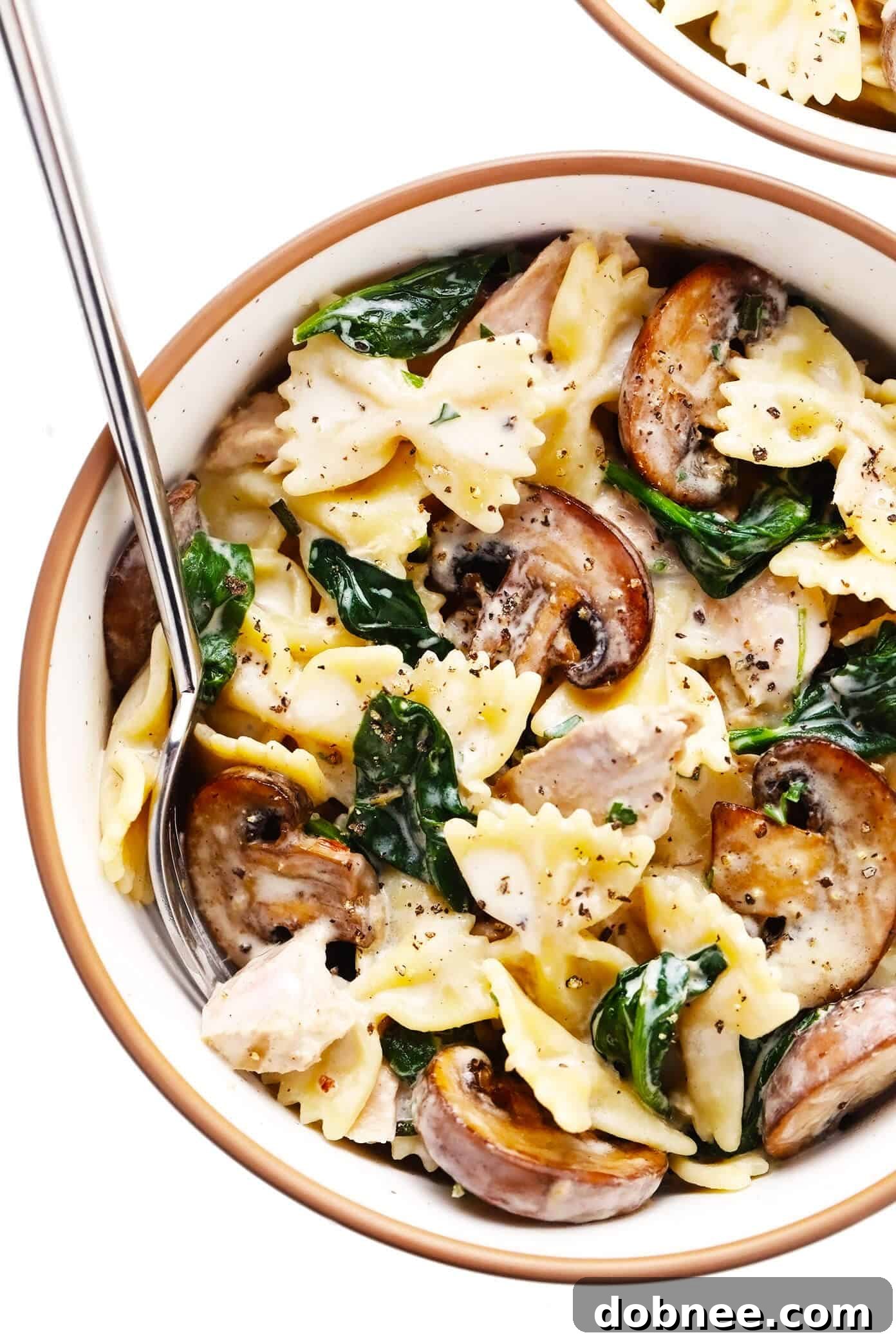 A generous serving of creamy tuna mushroom pasta in a rustic bowl, garnished with fresh herbs and Parmesan.