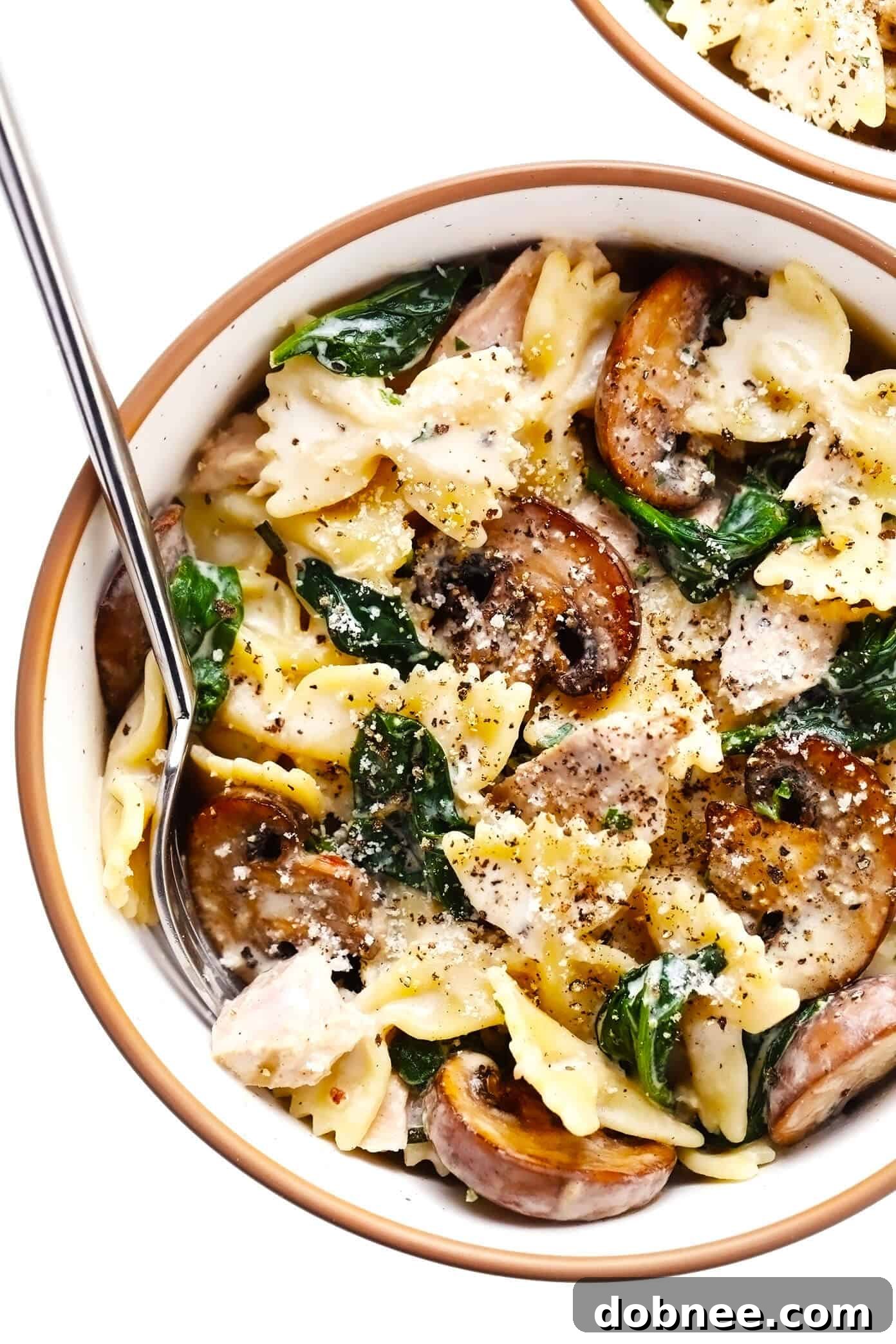 Creamy tuna mushroom pasta in a serving bowl, generously topped with freshly grated Parmesan cheese and black pepper, ready to be enjoyed.