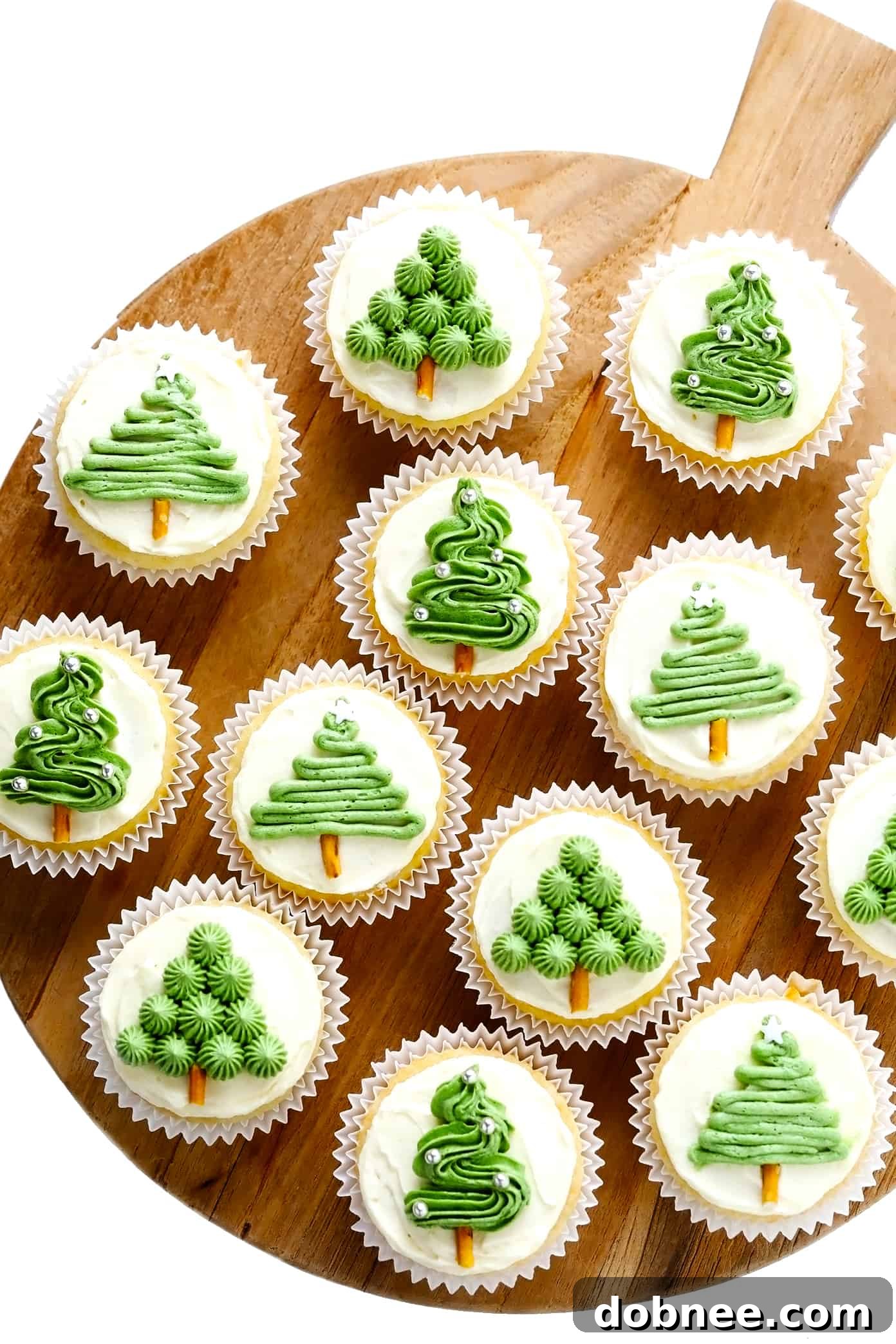 Decorated Christmas Tree Cupcakes artfully arranged on a rustic wooden tray, ready for serving.