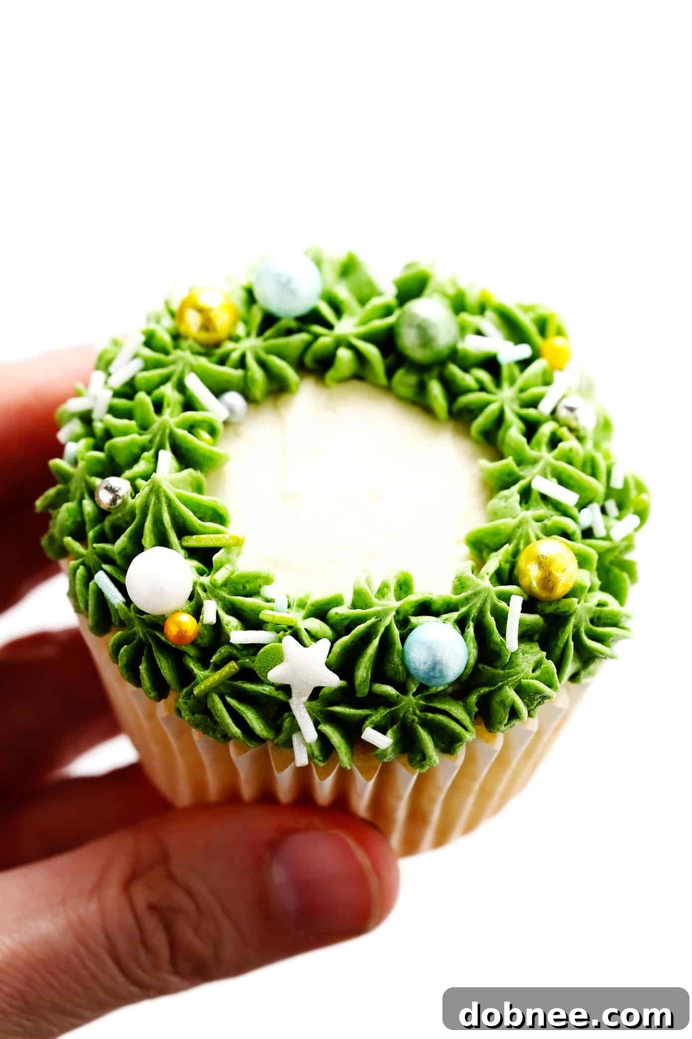 Detailed close-up of a single Christmas Wreath Cupcake, showcasing green frosting and festive sprinkles.