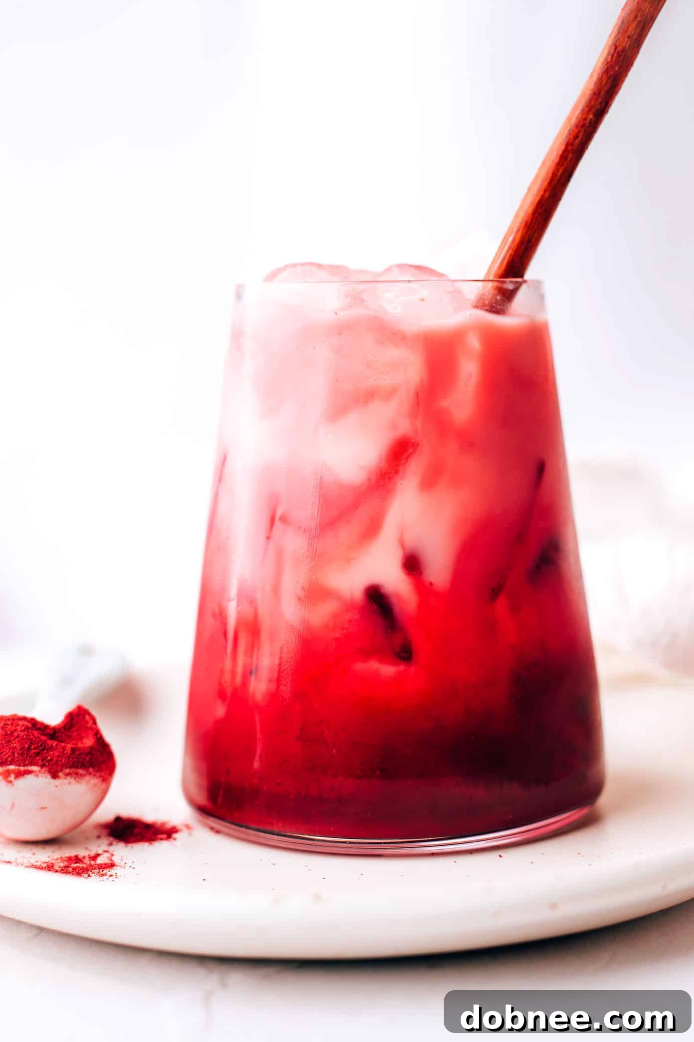 Refreshing Iced Pink Beetroot Latte, garnished with a pink straw and flowers.