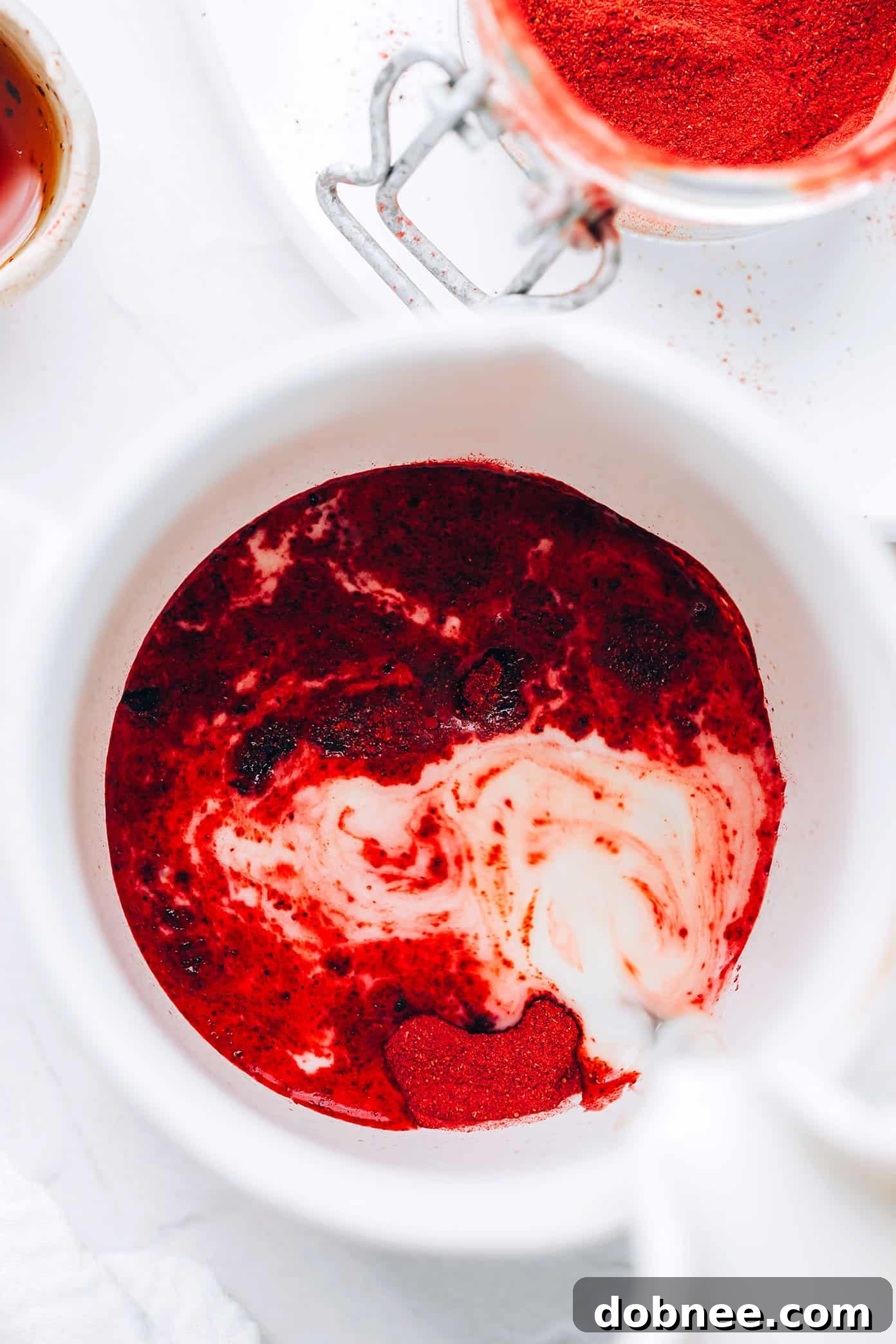Close-up of frothed milk being poured into a vibrant pink beetroot latte base.