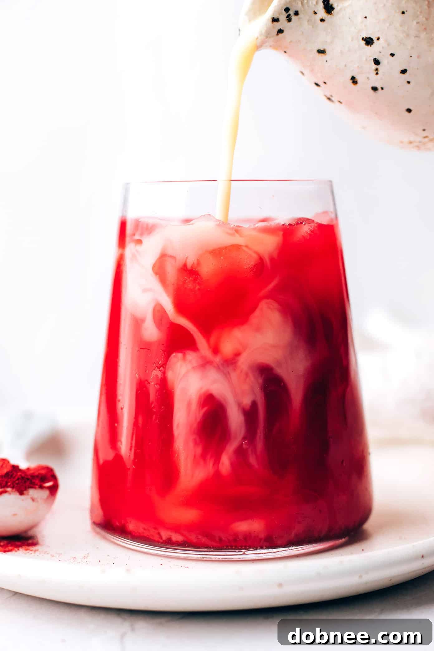 Preparing an Iced Pink Beetroot Latte: pouring cold milk over the mix and ice.