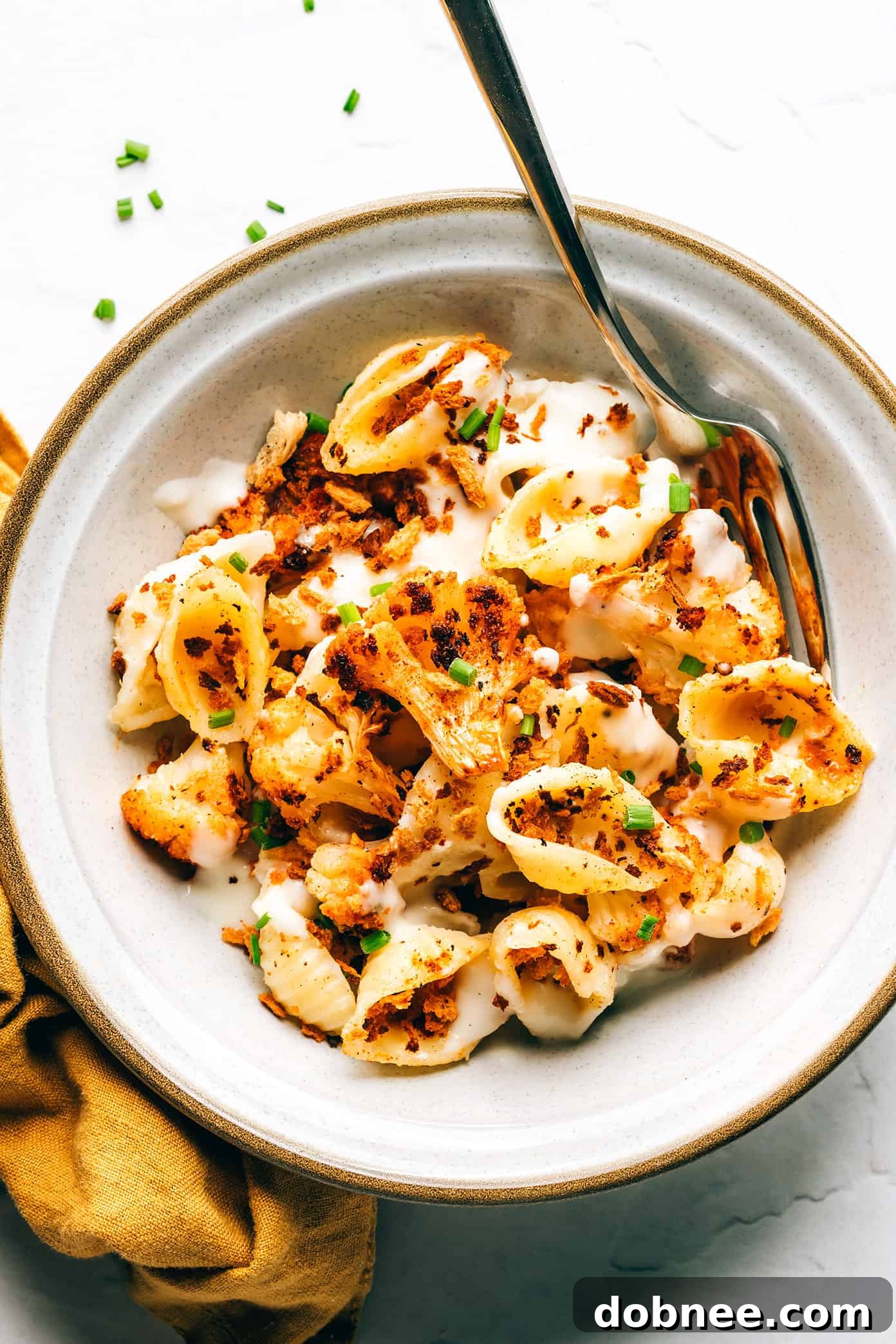 A comforting bowl of Roasted Cauliflower Mac and Cheese, perfect for dinner Individual serving of Roasted Cauliflower Mac and Cheese in a bowl with a fork