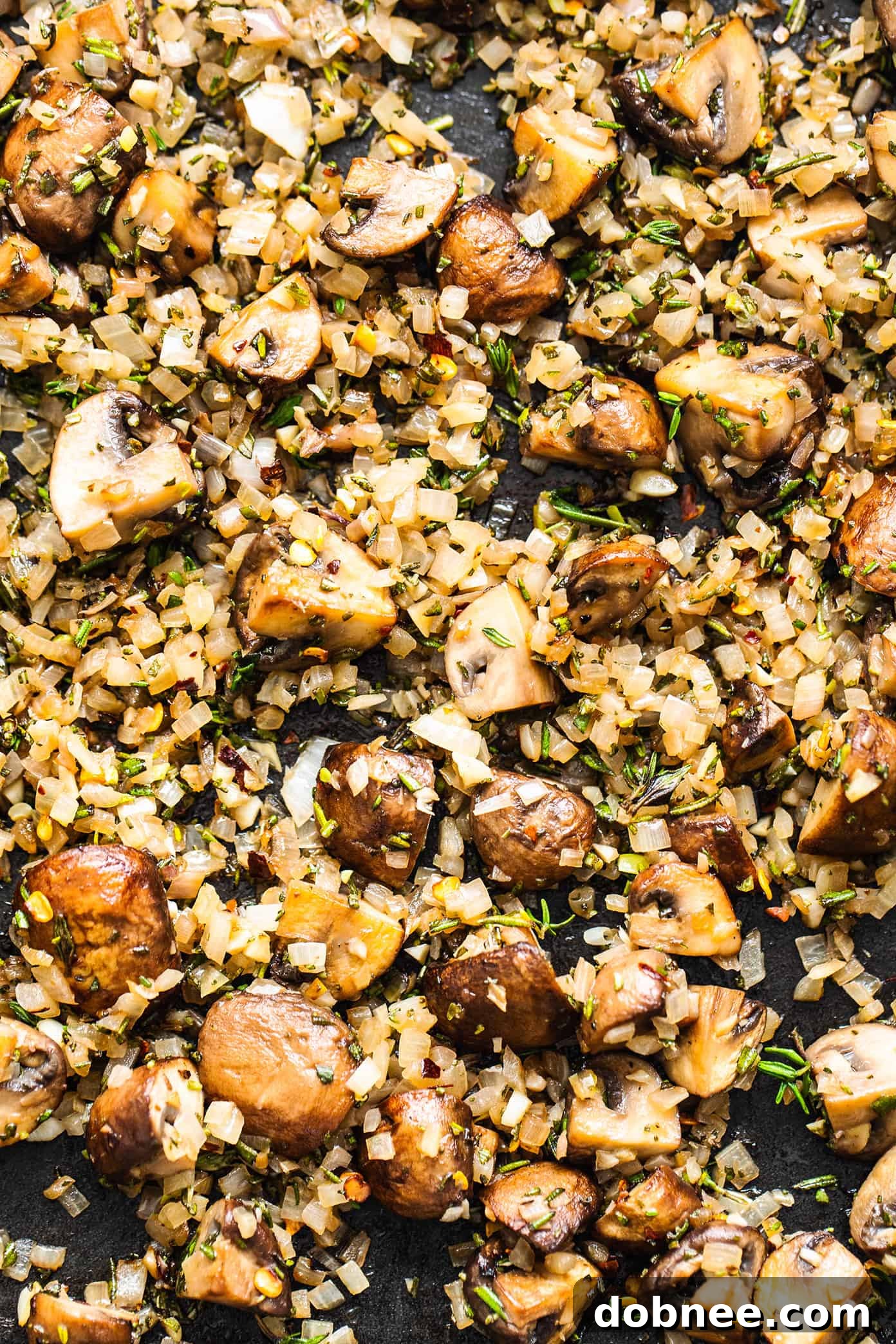 Sautéed shallots, mushrooms, and fresh herbs cooking in a pan for Pasta Boscaiola