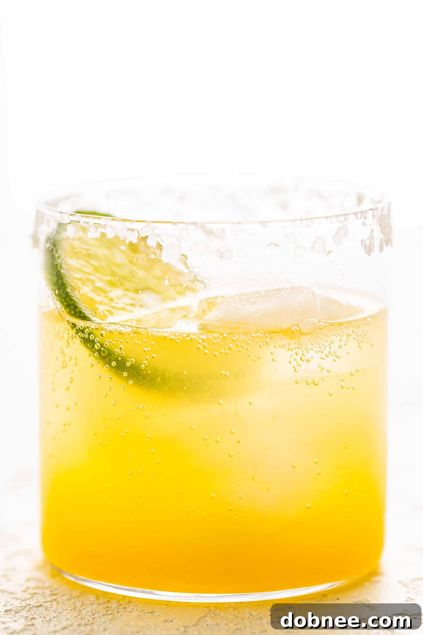 A vibrant Virgin Margarita Mocktail garnished with a lime slice and a salt rim, perfect for a refreshing non-alcoholic drink.