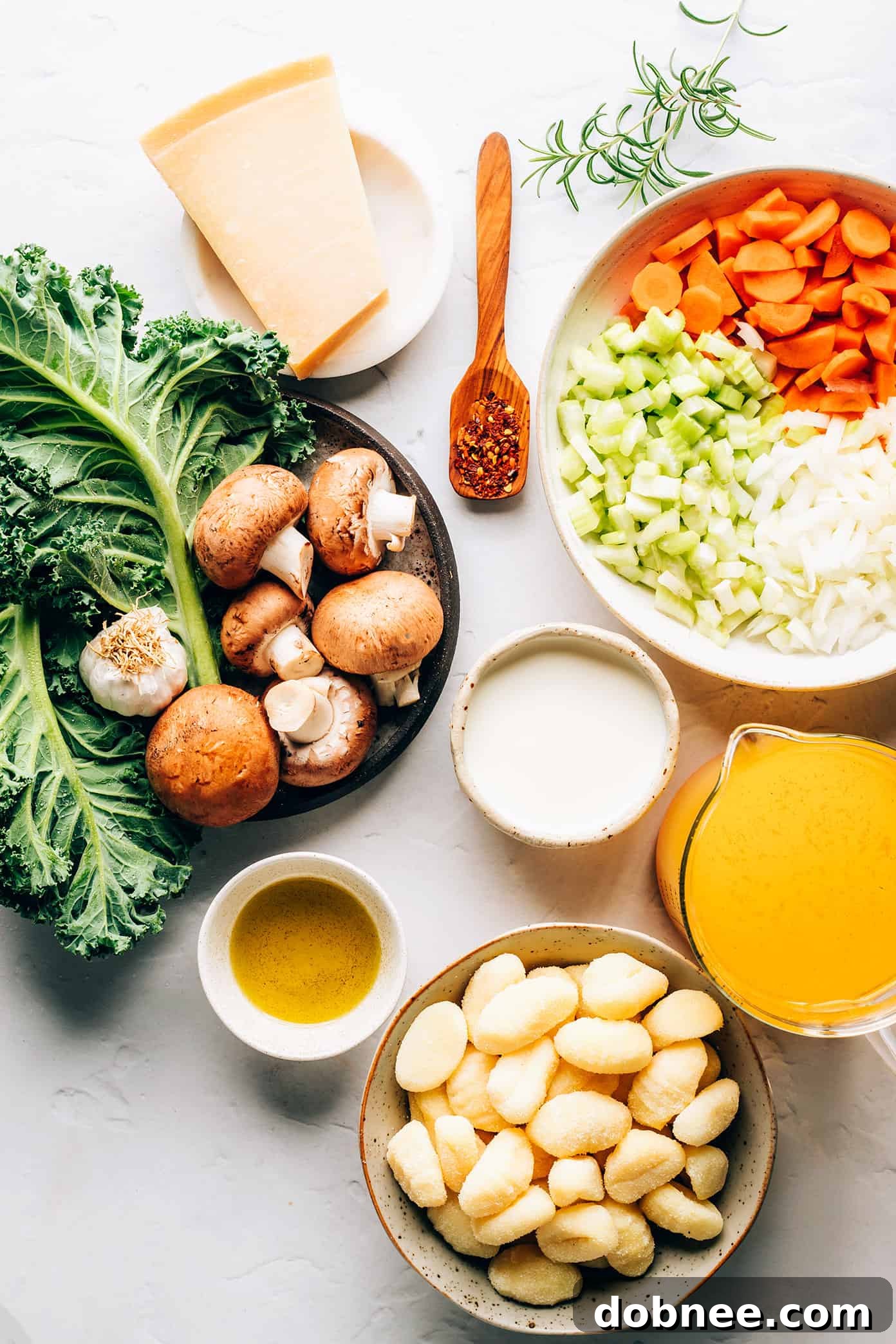 Fresh ingredients for Gnocchi, Mushroom and Kale Soup laid out, including gnocchi, mushrooms, kale, carrots, celery, and onion.