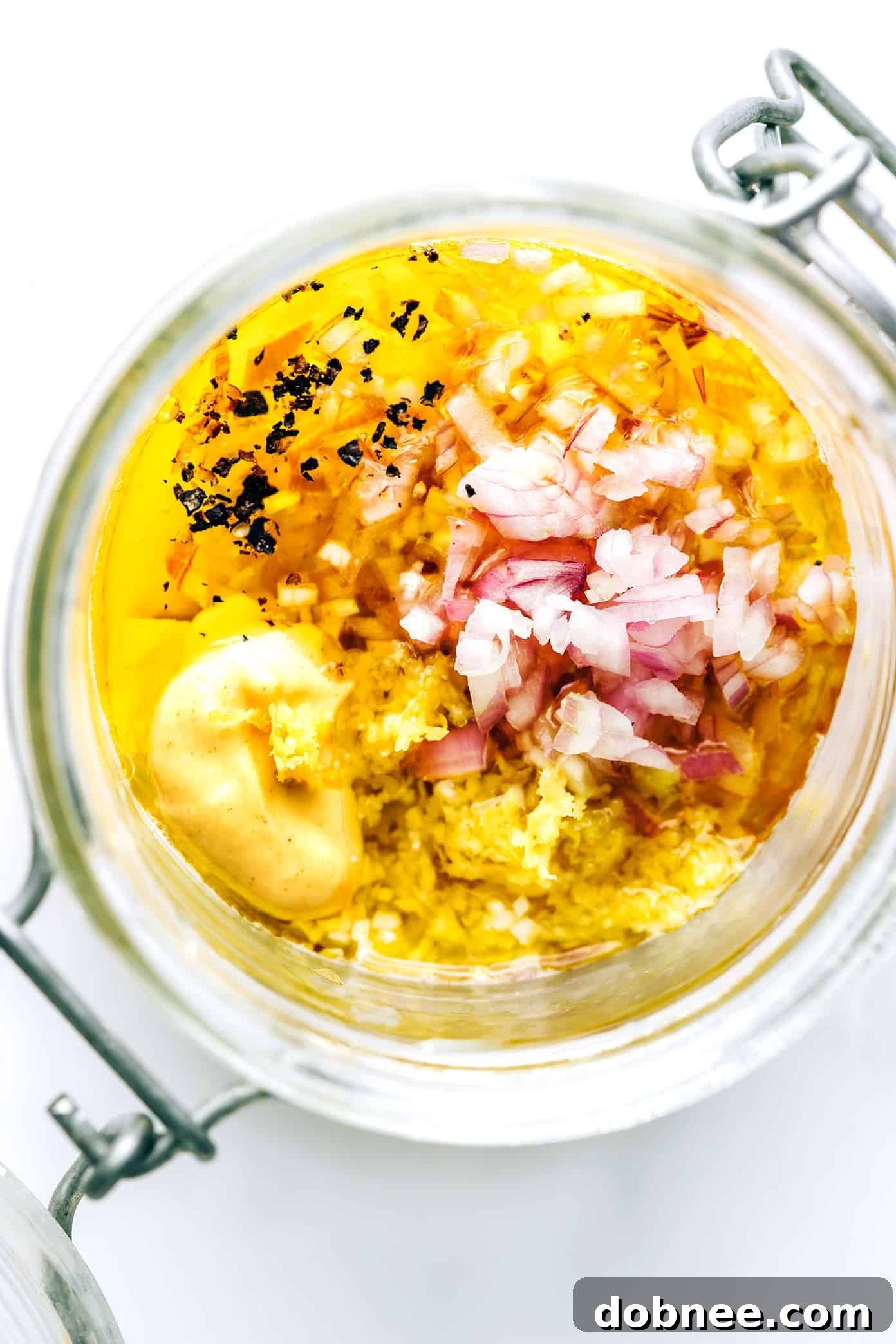 Shallot Vinaigrette in a clear glass jar on a wooden surface, showing its delicate texture