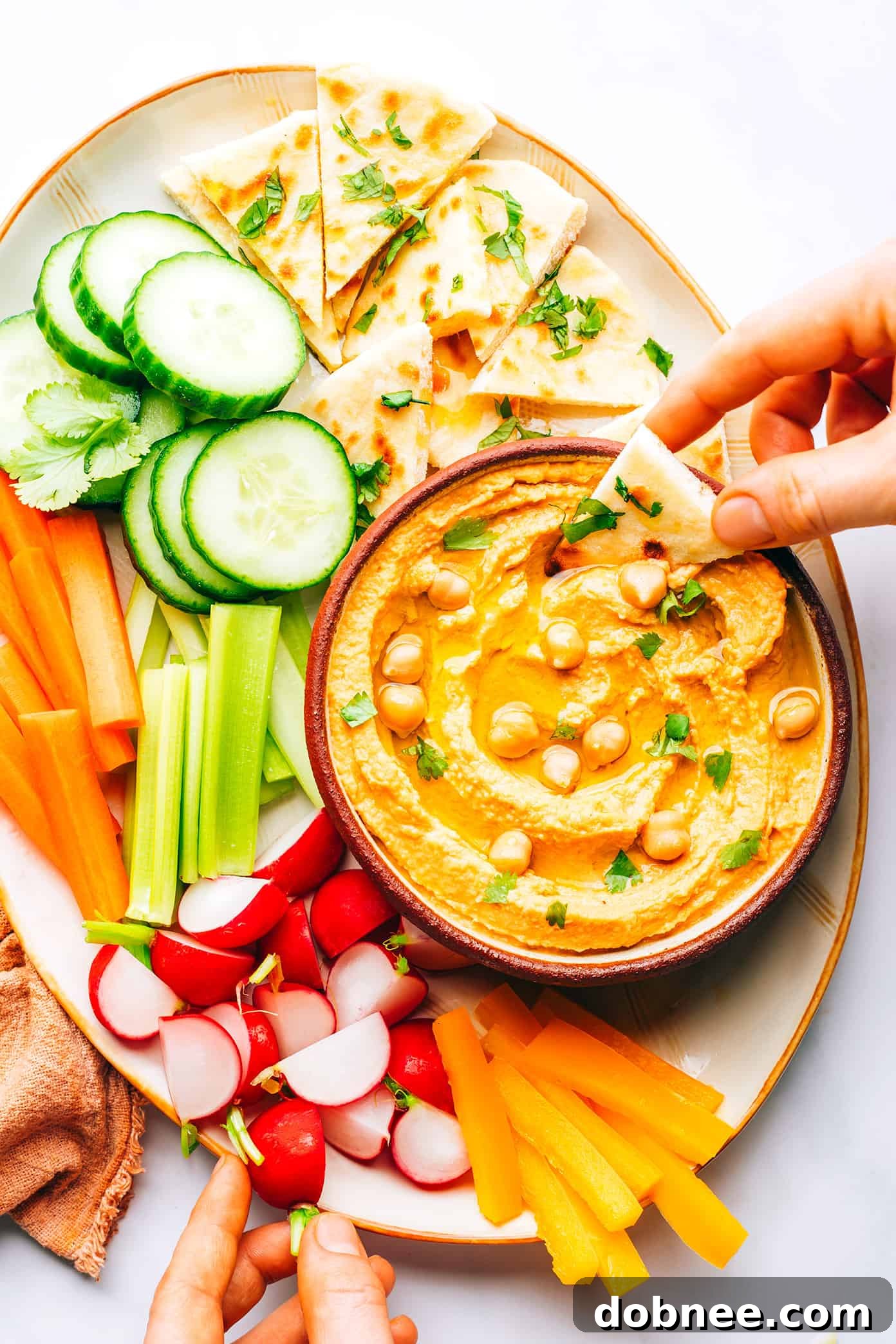 Platter of Thai Red Curry Hummus with various dippers like crudités and naan bread