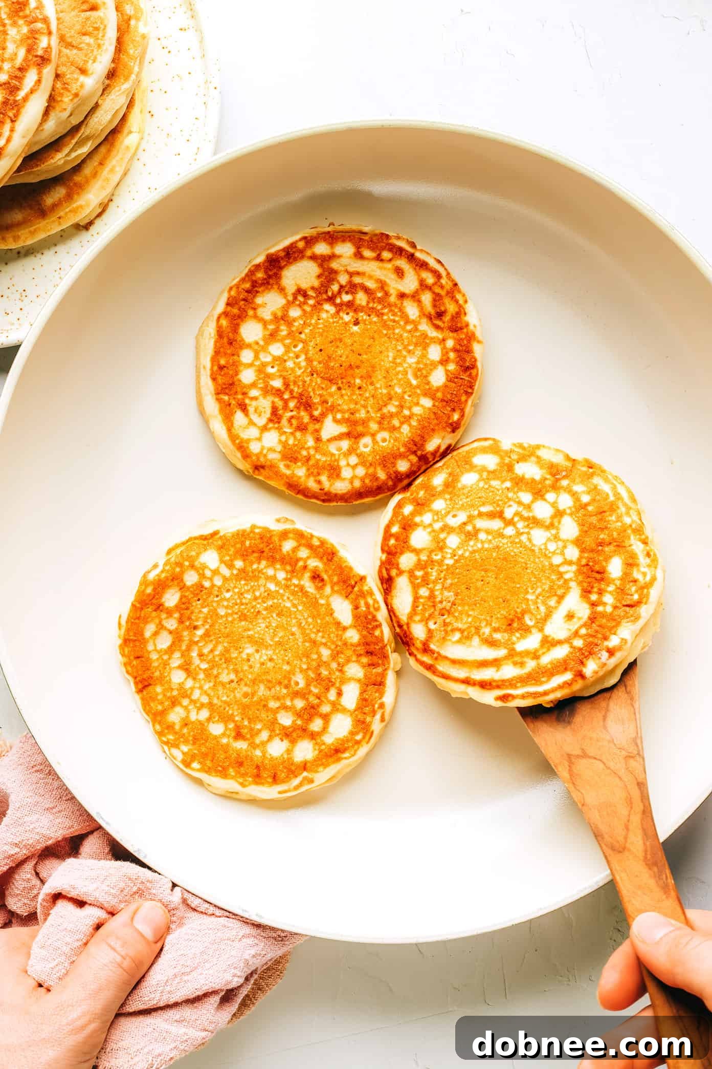 Close-up of a stack of golden kefir pancakes with a knob of butter melting on top, ready to be drizzled with syrup