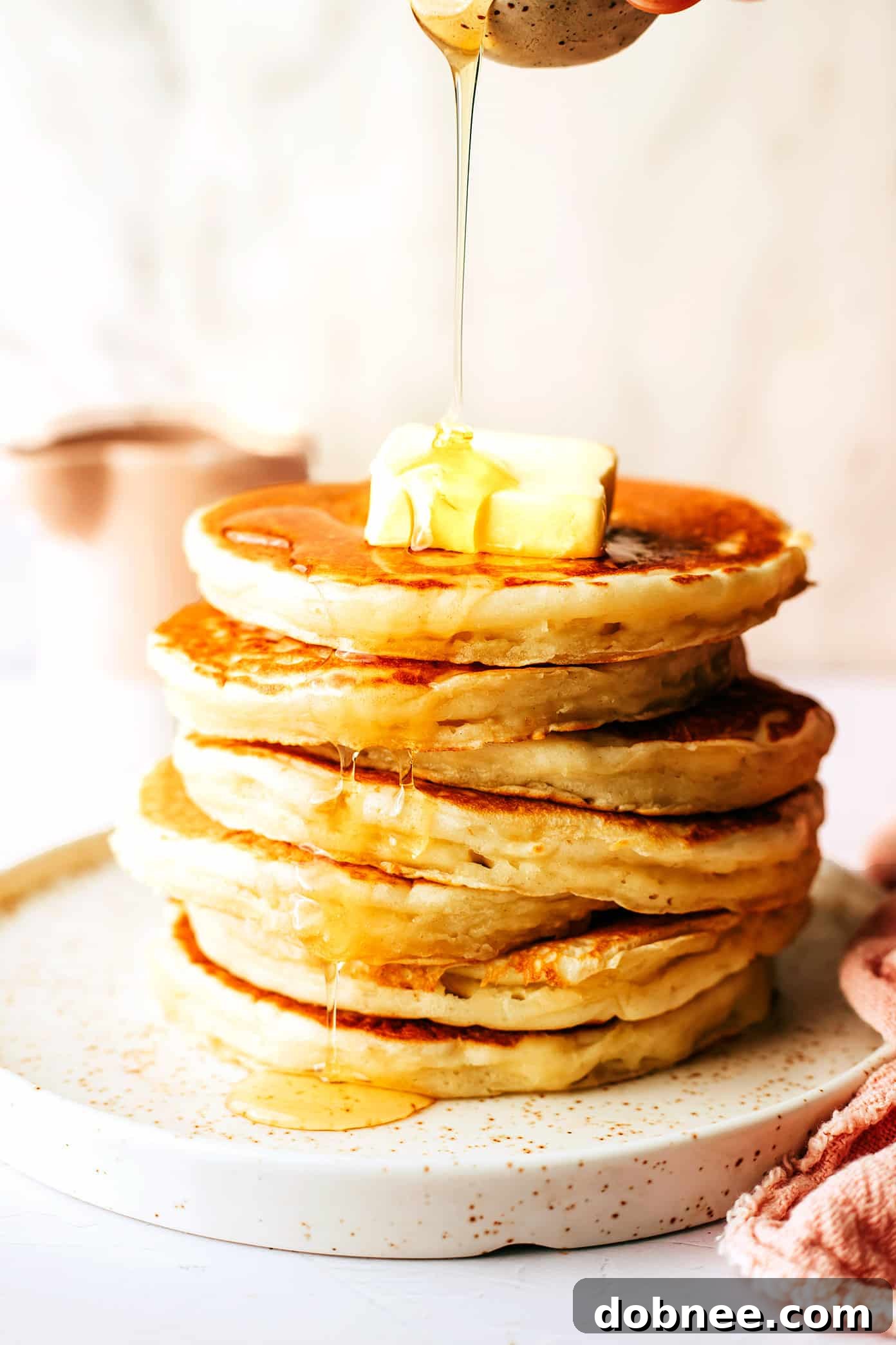 A close-up of a single kefir pancake being generously drizzled with pure maple syrup