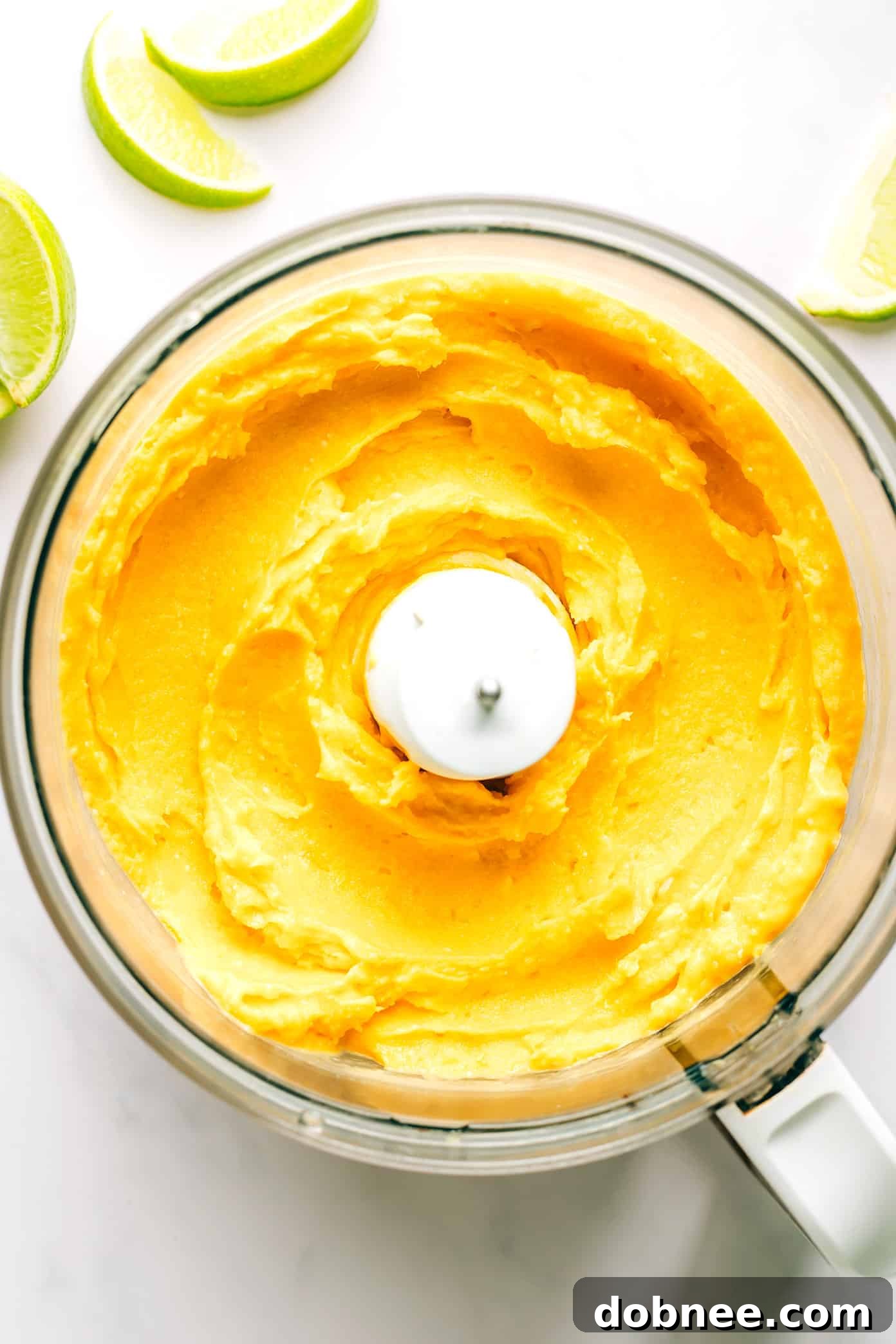 Close-up of Mango Lime Sorbet being blended in a food processor, showing its creamy texture