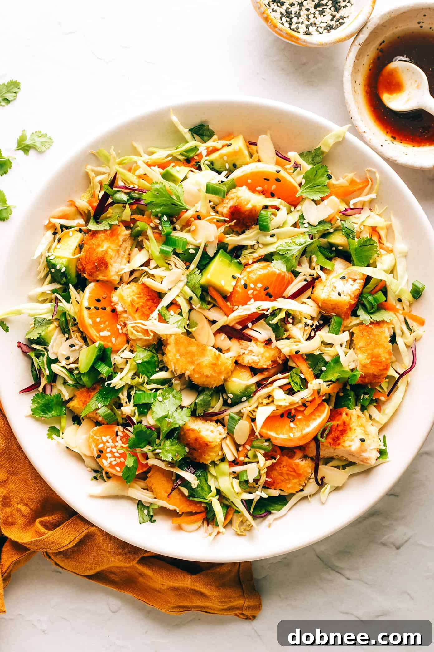 Ingredients on a cutting board including breaded chicken, mandarins, and cilantro