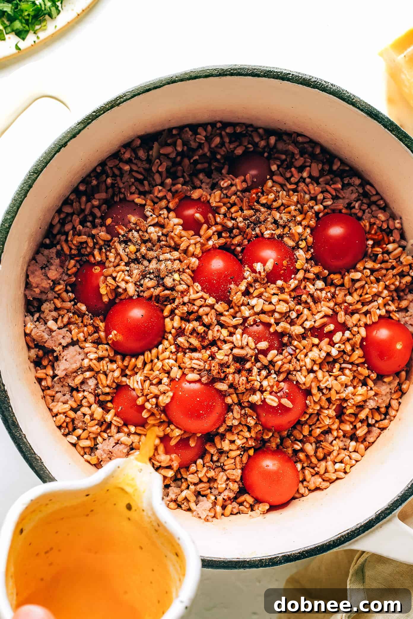 Adding broth to one pot farro with Italian sausage and tomatoes - Key Step