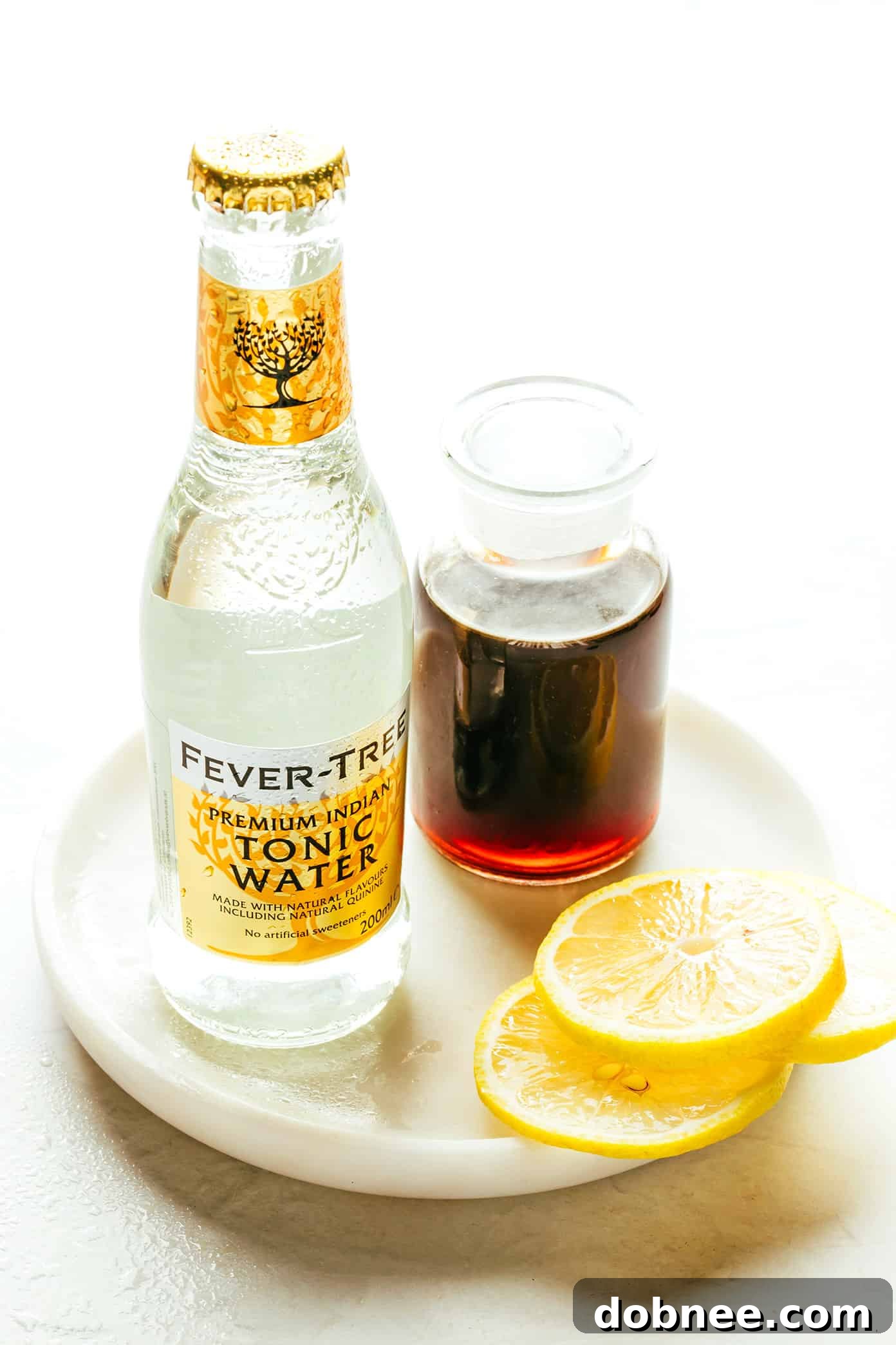 Key ingredients for Cold Brew Tonic arranged: cold brew concentrate, tonic water, and a fresh lemon