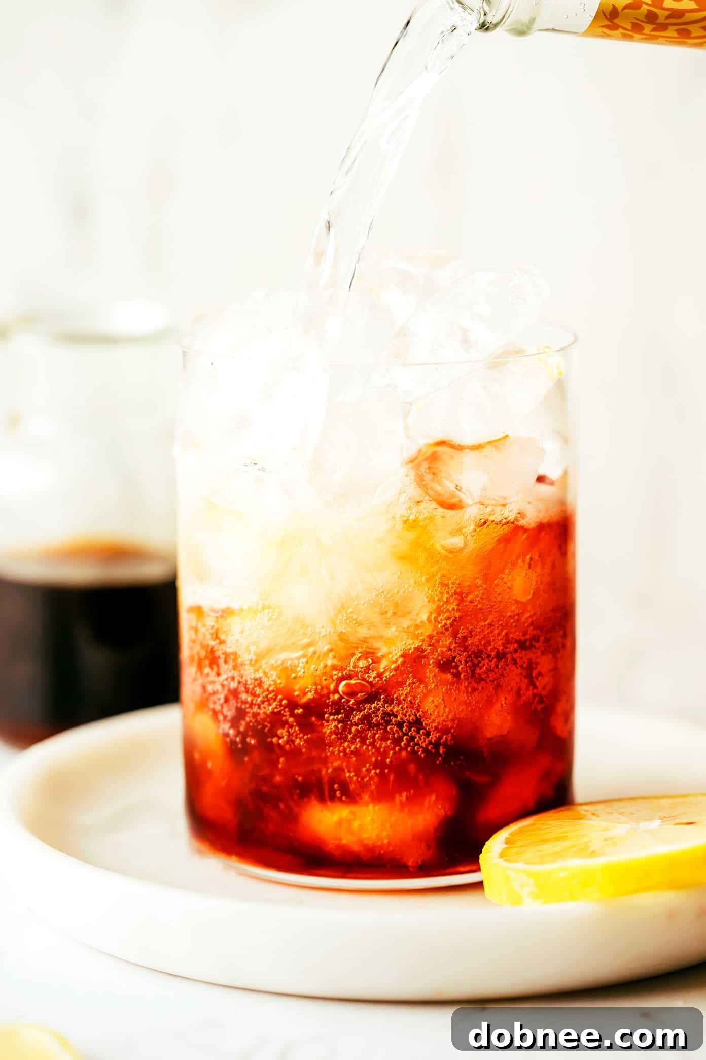 The moment of creation: tonic water being poured into a glass with cold brew concentrate and ice