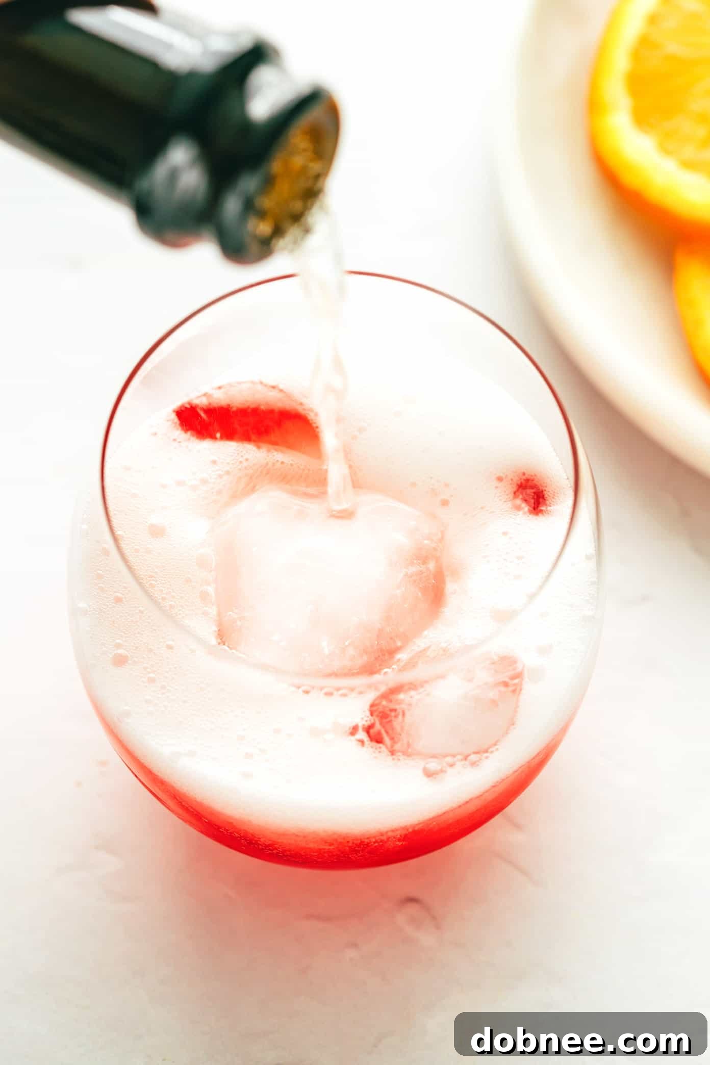 A beautifully composed flat lay image showing all the ingredients for a Campari Spritz: a bottle of Campari, a bottle of prosecco, club soda, ice, and fresh oranges.