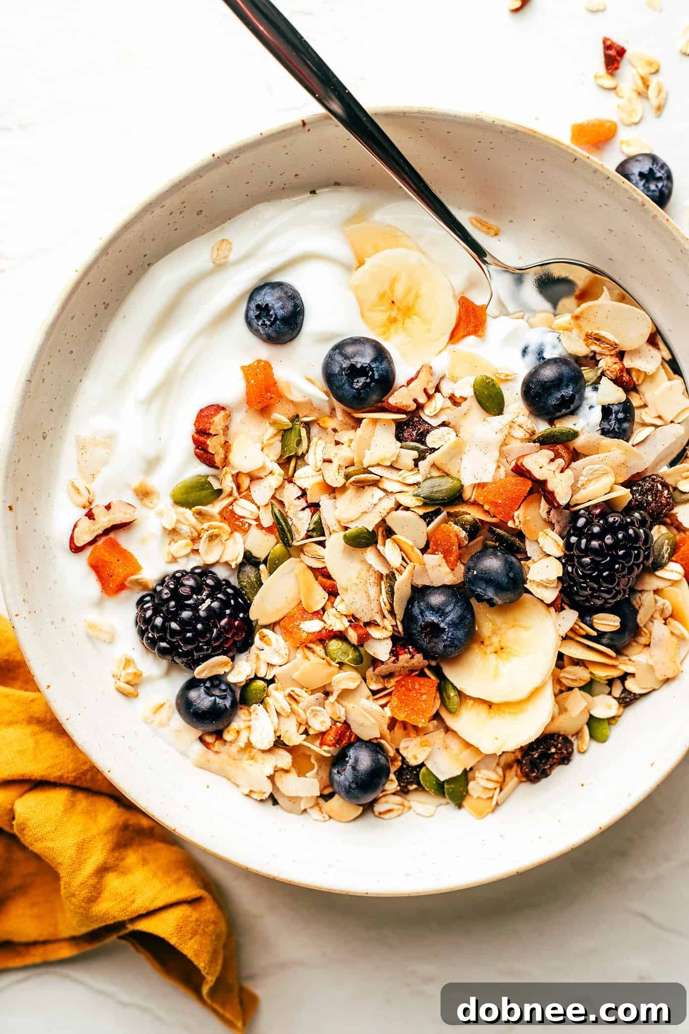 A vibrant breakfast bowl featuring homemade muesli, creamy Greek yogurt, fresh berries, and sliced bananas.