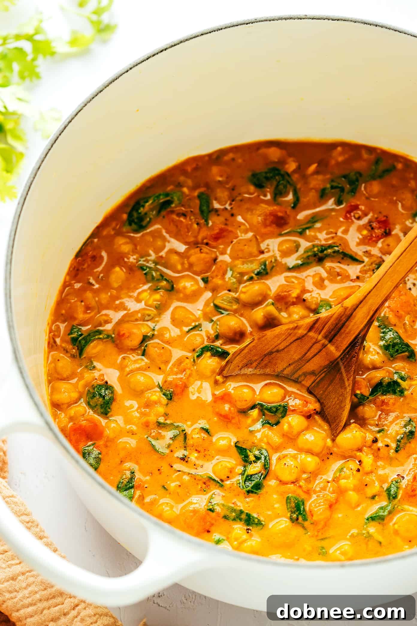 Rich Chickpea Curry Simmering in a Pot with a Wooden Spoon