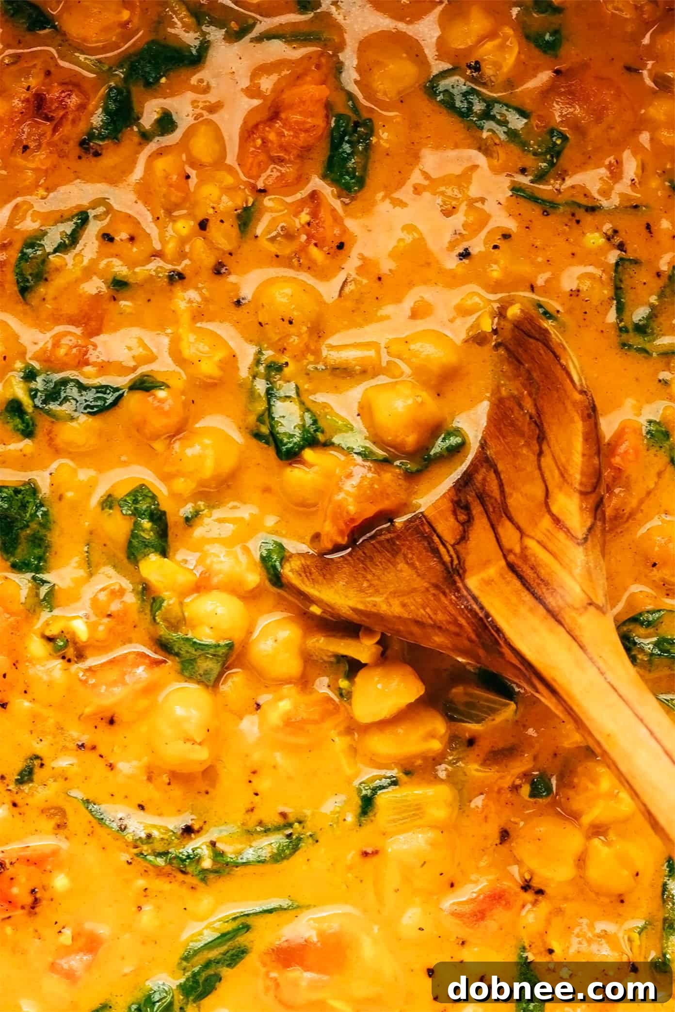 Closeup of Creamy Chickpea Curry with a Wooden Spoon