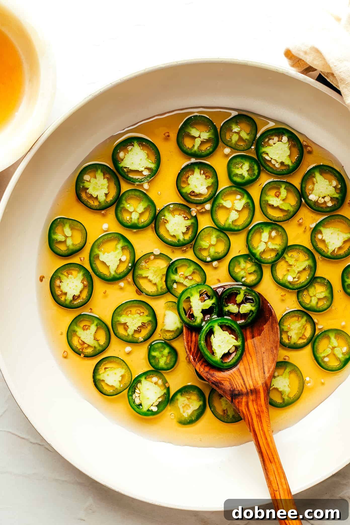 This homemade hot honey recipe is quick and easy to make with 3 ingredients and tastes delicious drizzled on everything from pizza to biscuits, fried chicken, salmon, veggies, baked brie and more! | gimmesomeoven.com Making homemade hot honey with sliced jalapeno peppers