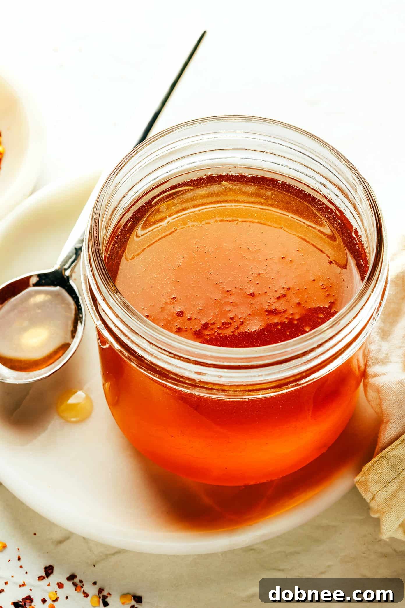 This homemade hot honey recipe is quick and easy to make with 3 ingredients and tastes delicious drizzled on everything from pizza to biscuits, fried chicken, salmon, veggies, baked brie and more! | gimmesomeoven.com Jar of Homemade Hot Honey with Chili Flakes