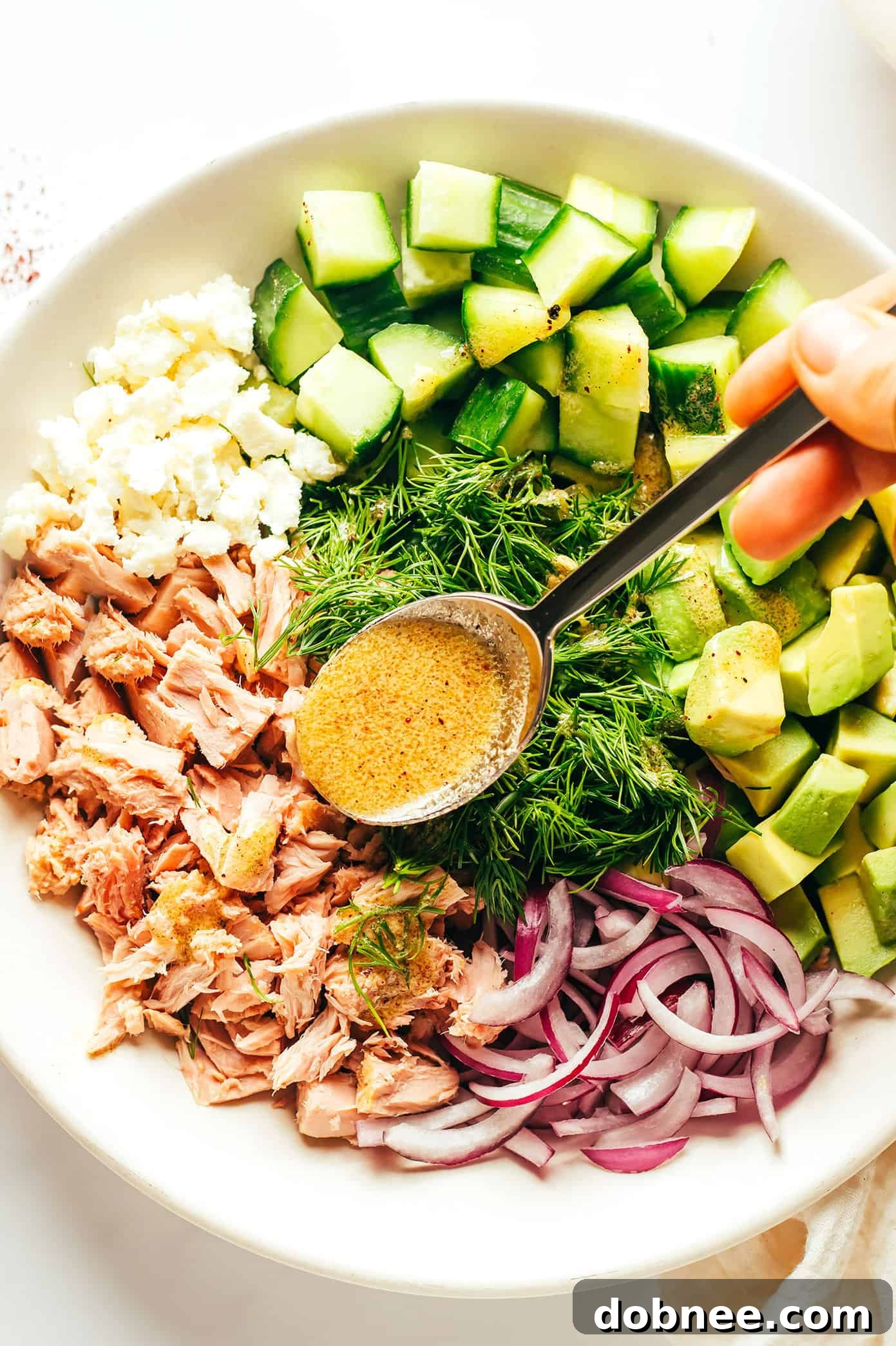 Adding lemon-sumac dressing to tuna avocado salad