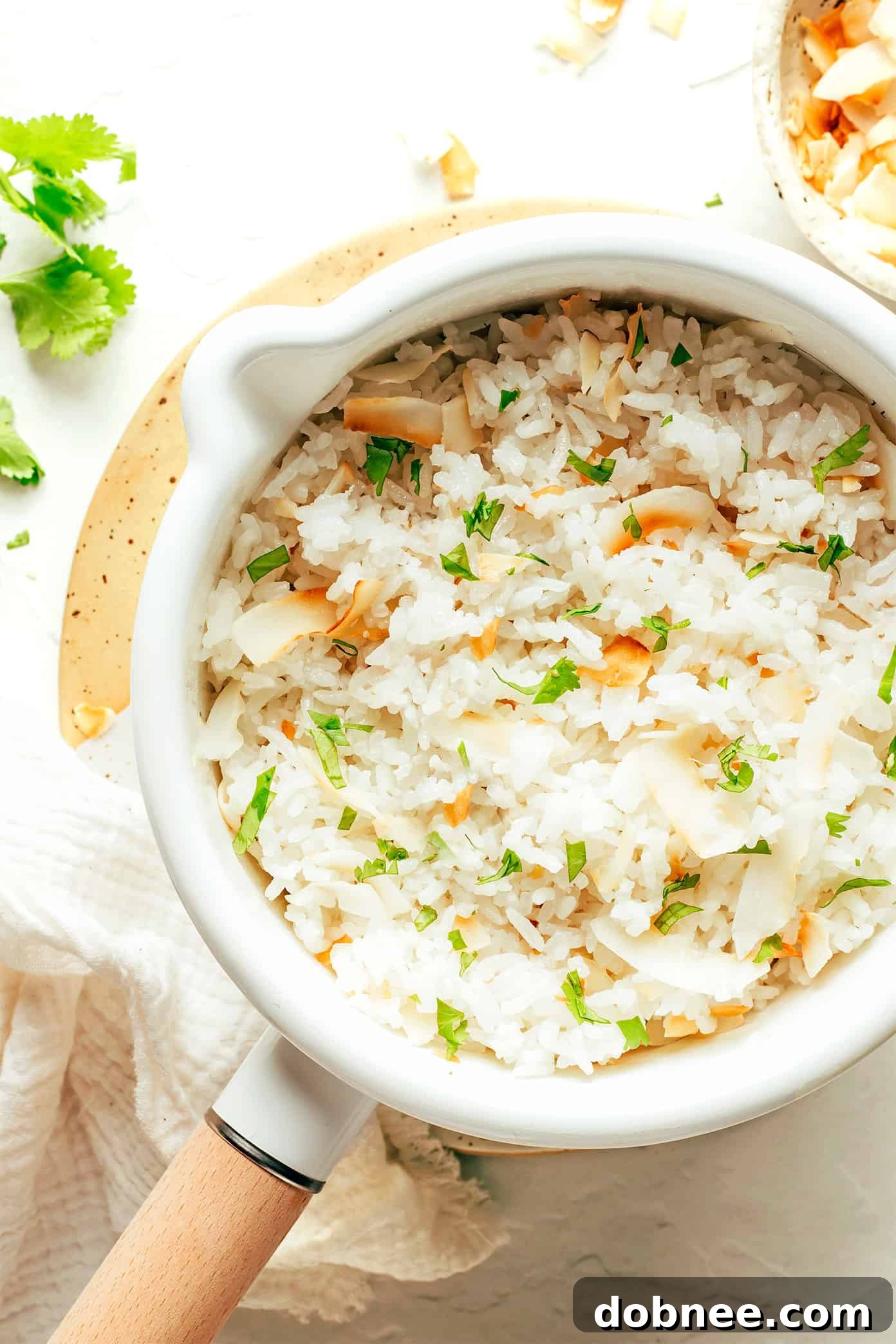 Close-up of fluffy coconut rice steaming in a saucepan, ready to be served.