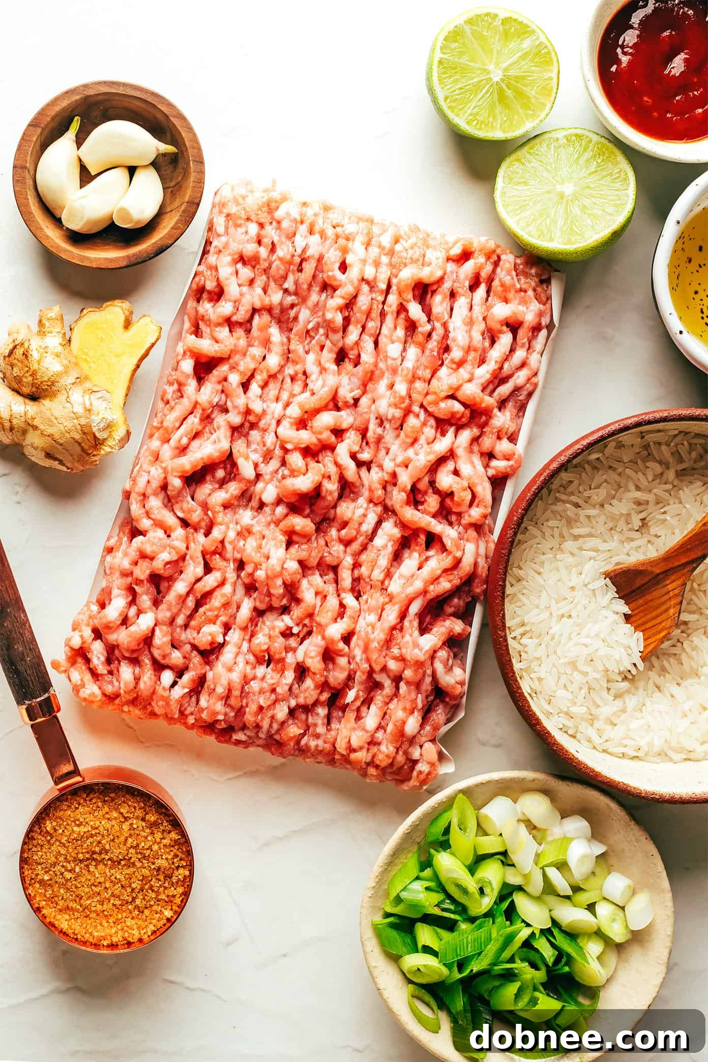 Fresh ingredients laid out for Ginger Lime Pork, including ginger, limes, scallions, garlic, and ground pork.