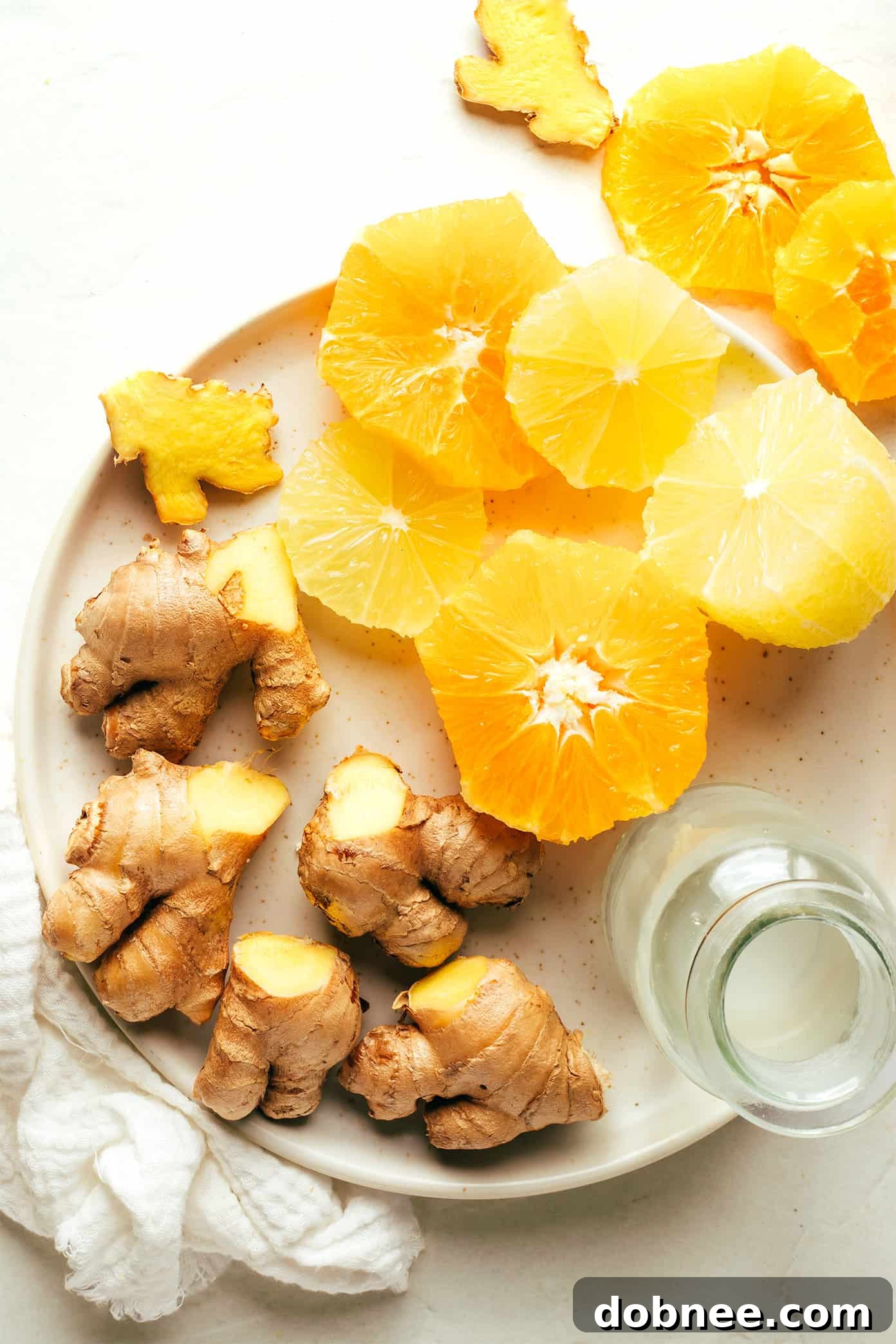 Ingredients for homemade ginger shots: fresh ginger, oranges, lemons, and coconut water.