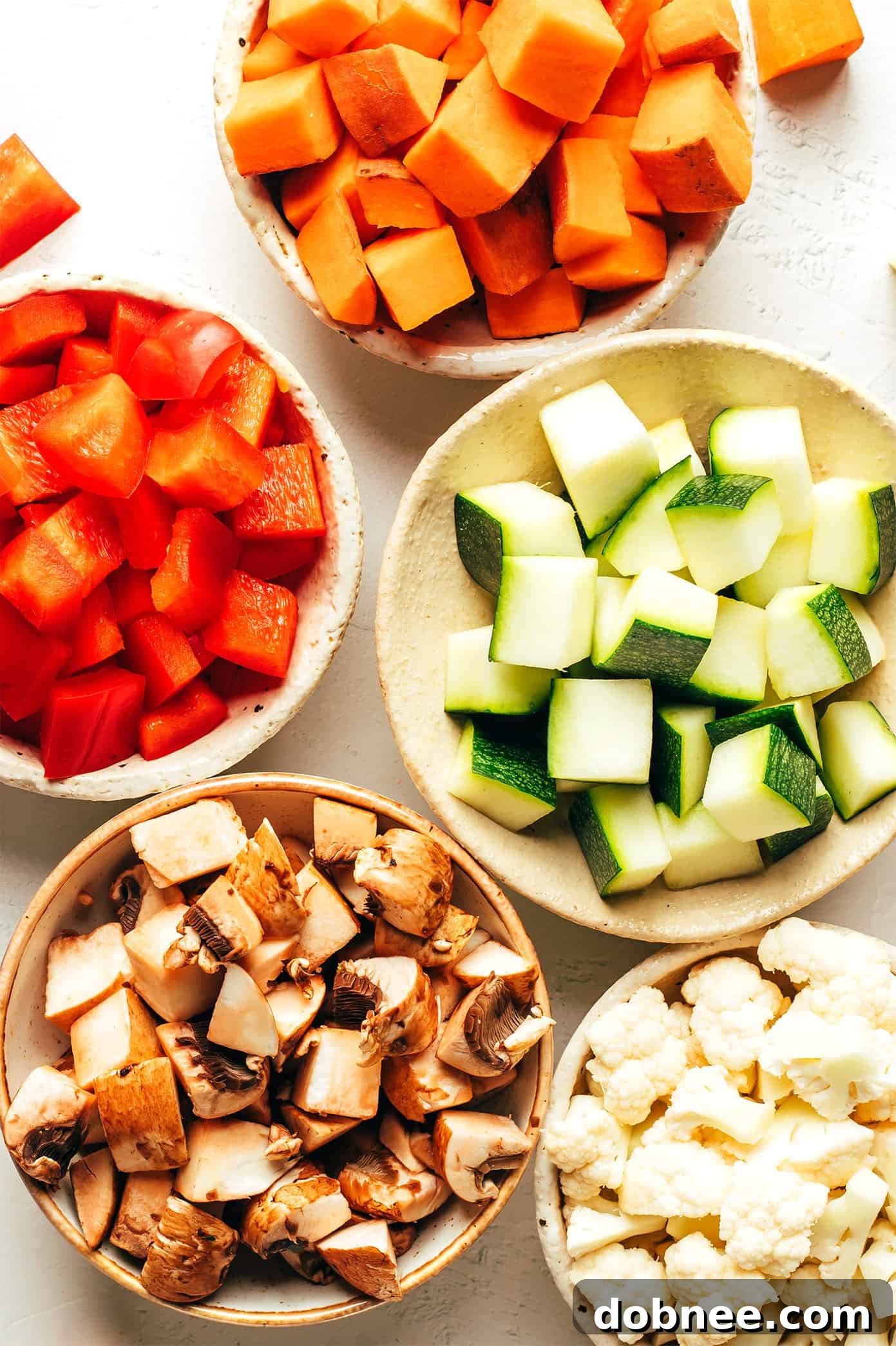 Ingredients laid out for Vegetarian Chili, including beans, diced vegetables (sweet potato, bell pepper, zucchini, mushrooms, cauliflower), tomatoes, and spices. This delicious recipe is easy to make and full of rich flavor, naturally gluten-free and vegan.