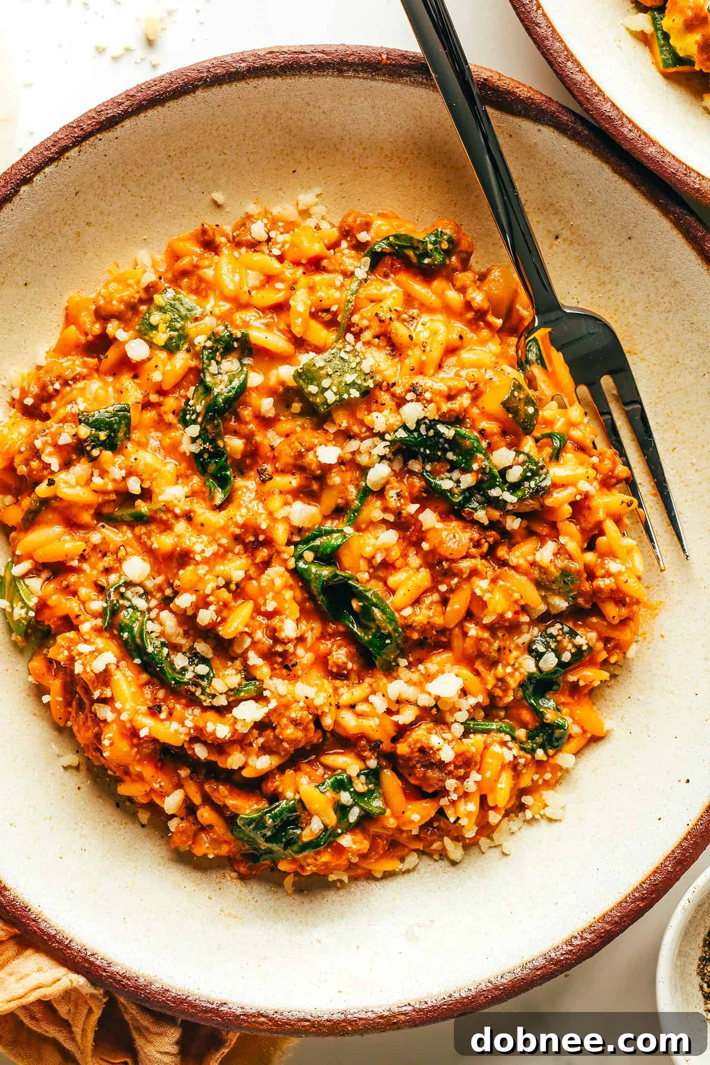 Close-up of a serving of Italian Sausage Zucchini Orzo with fresh basil and parmesan