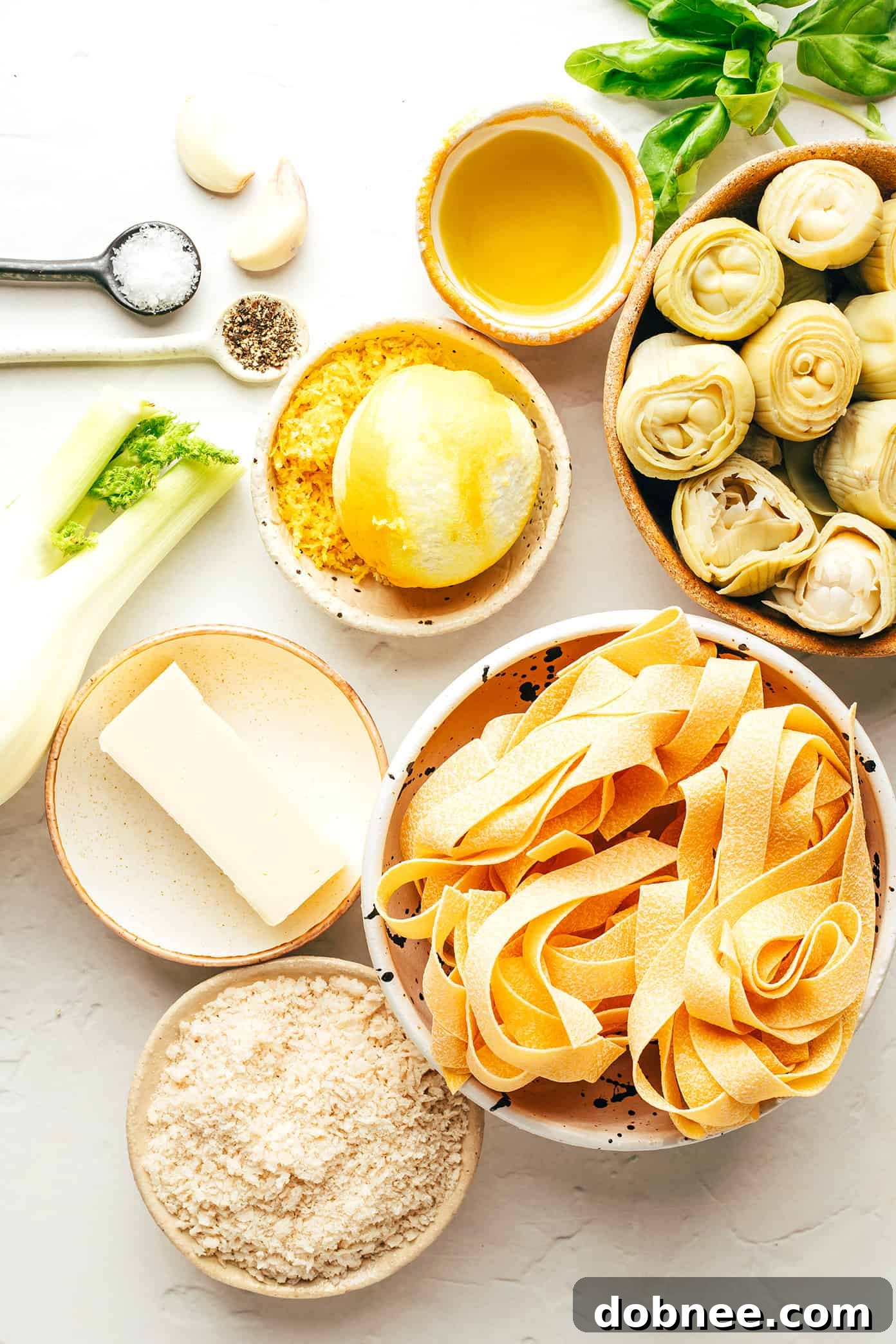 A collection of fresh ingredients laid out for Lemon Brown Butter Pasta, including fennel, artichokes, lemon, butter, garlic, and fresh basil.