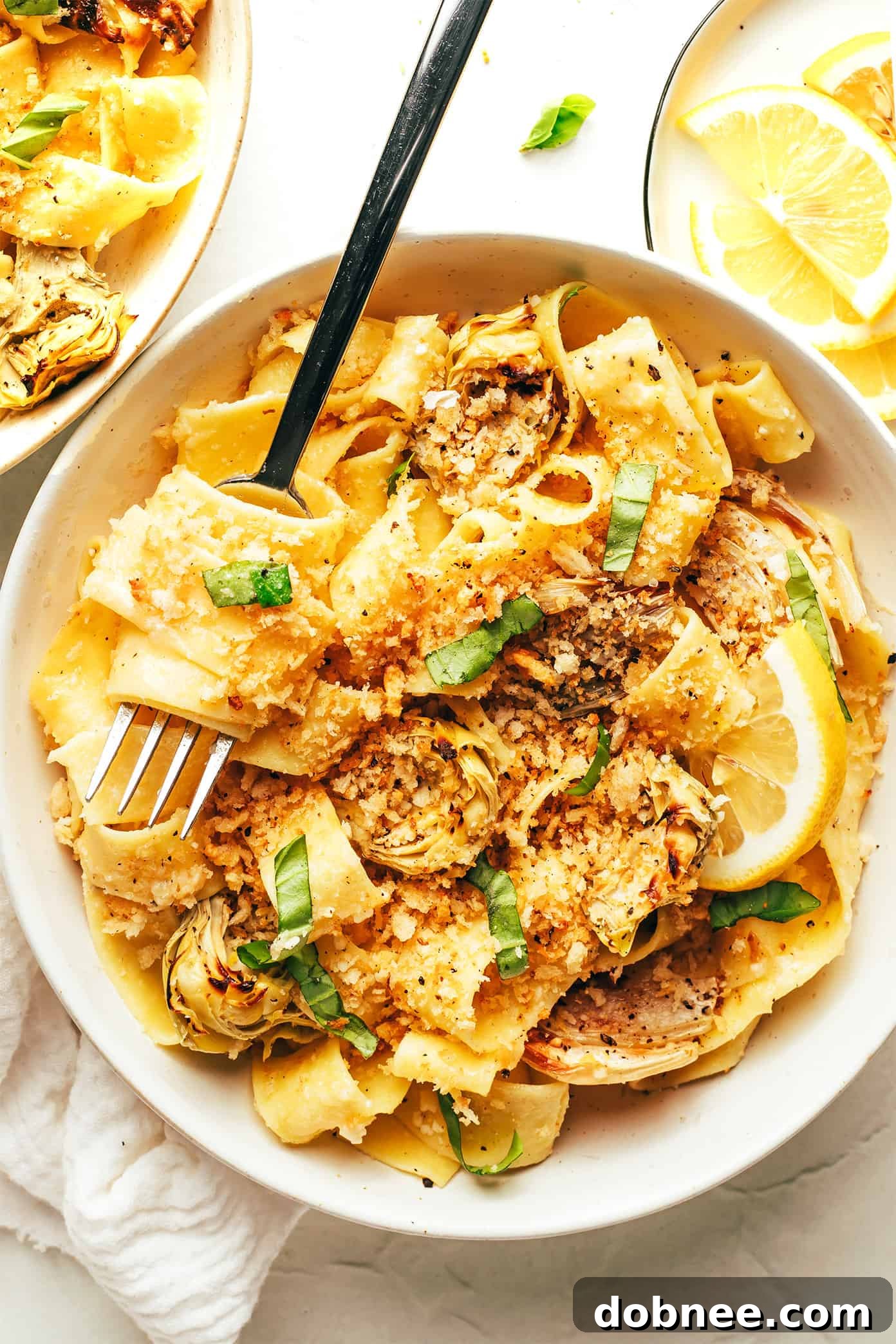A close-up of a generous serving of Lemon Brown Butter Pasta with Roasted Artichokes and Fennel, garnished with fresh basil and garlic breadcrumbs, ready to be enjoyed.