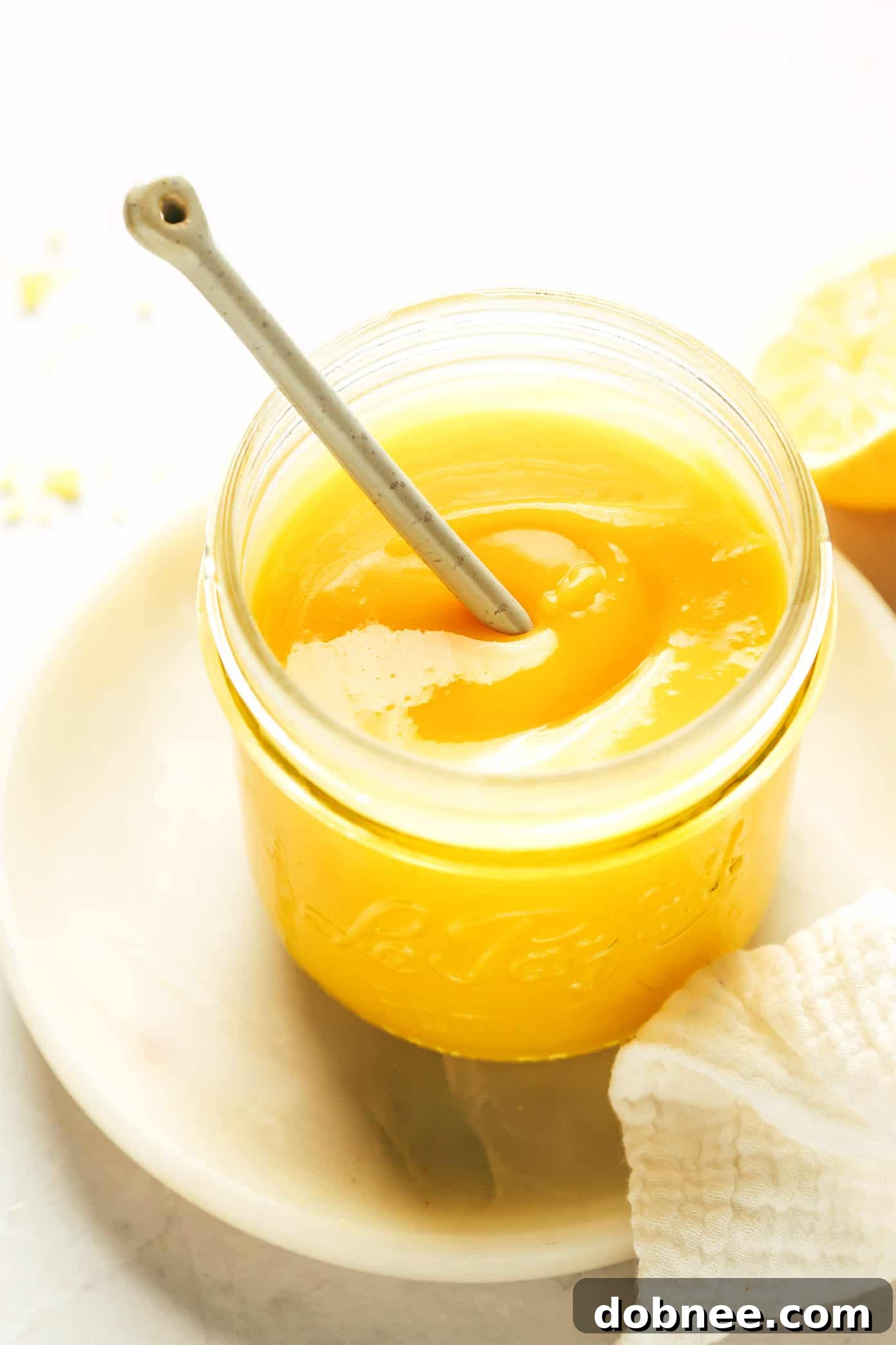 A large glass jar filled with freshly made, golden homemade lemon curd, ready to be enjoyed or stored.