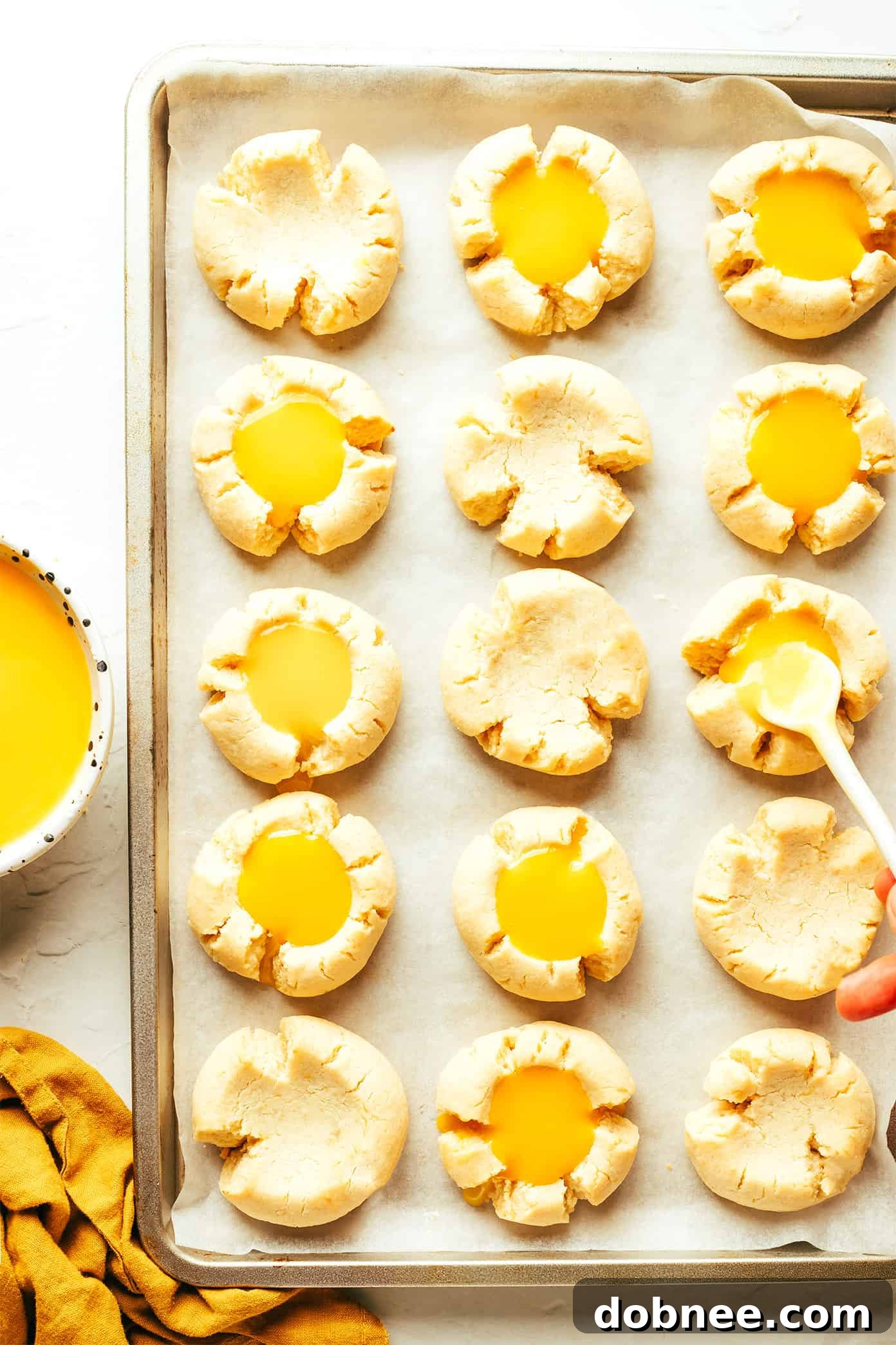Delicious lemon curd thumbprint cookies, showing the curd's glossy texture nestled in the center of golden cookies.