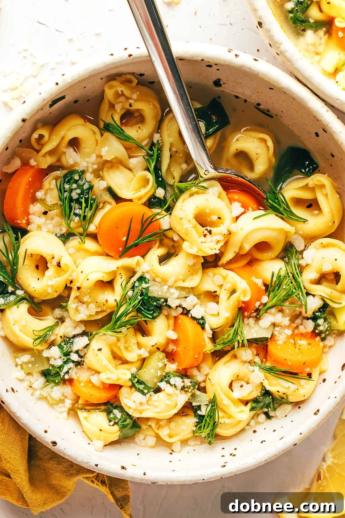 Five bowls of Lemony Tortellini Soup served on a table.
