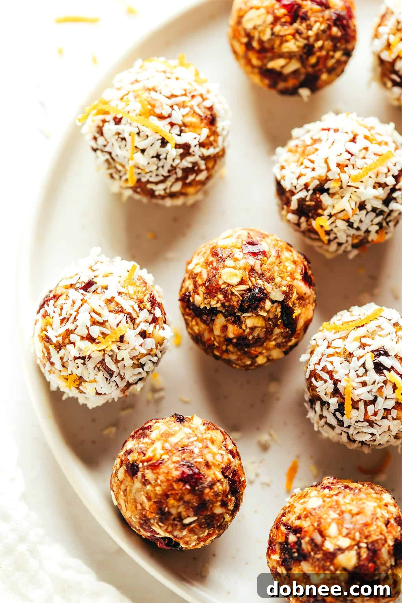 A stack of Cranberry Orange Almond Energy Bites, one sliced in half to show the texture.